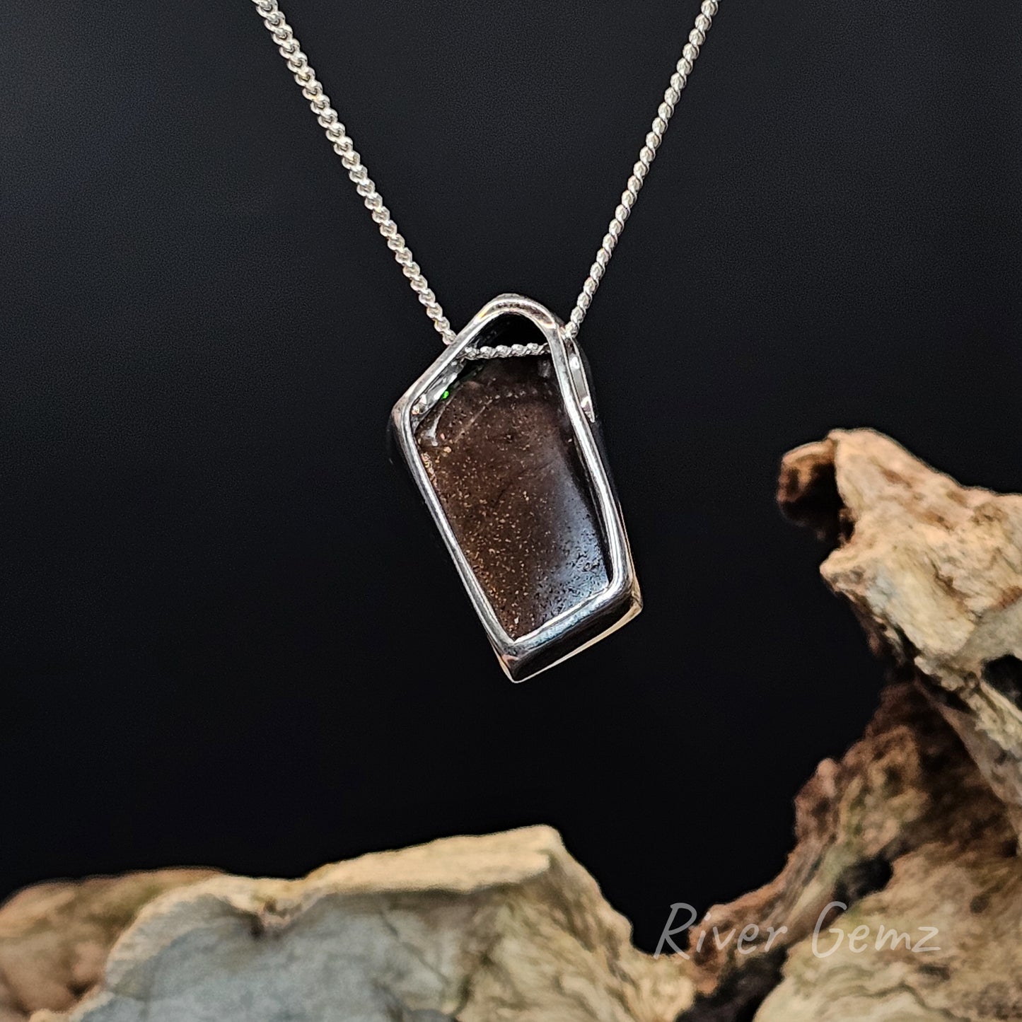 Rear view of the necklace shows the ironstone matrix of the boulder opal set in it on a dark background