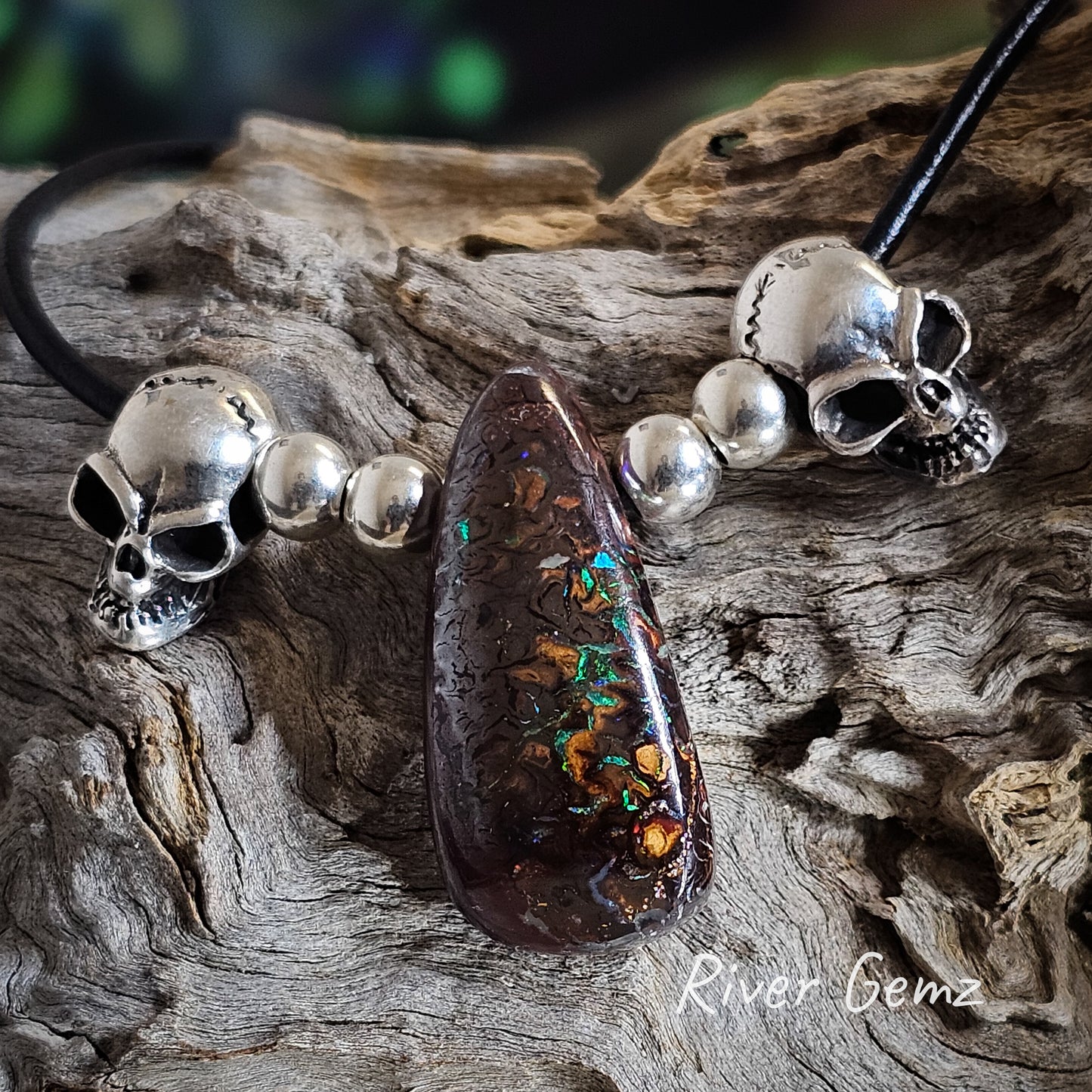 Dark ironstone host of boulder opal showing veins of colour in the pendant.