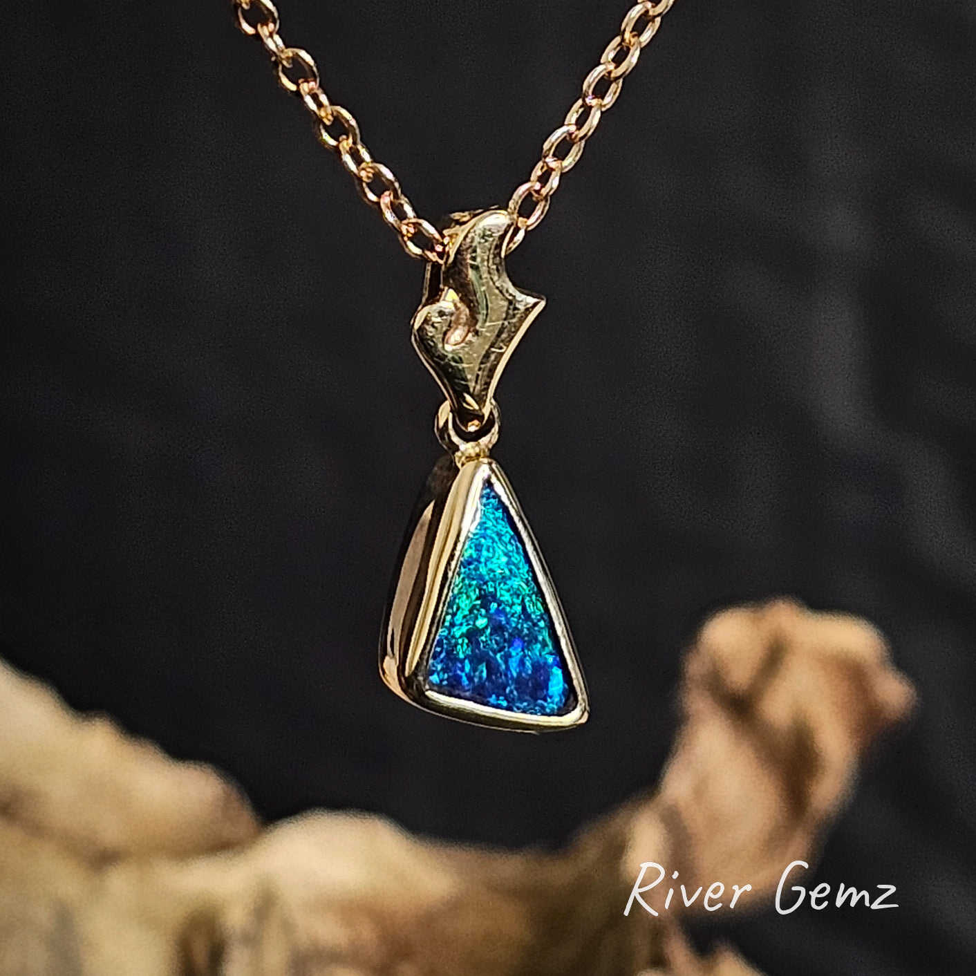 Gold necklace with a blue triangular pendant on a dark background