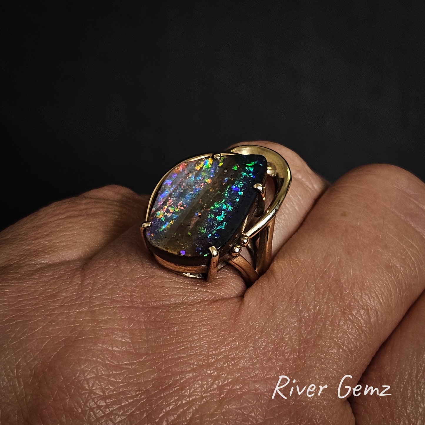 Boulder opal in gold ring shown worn on the ring finger.