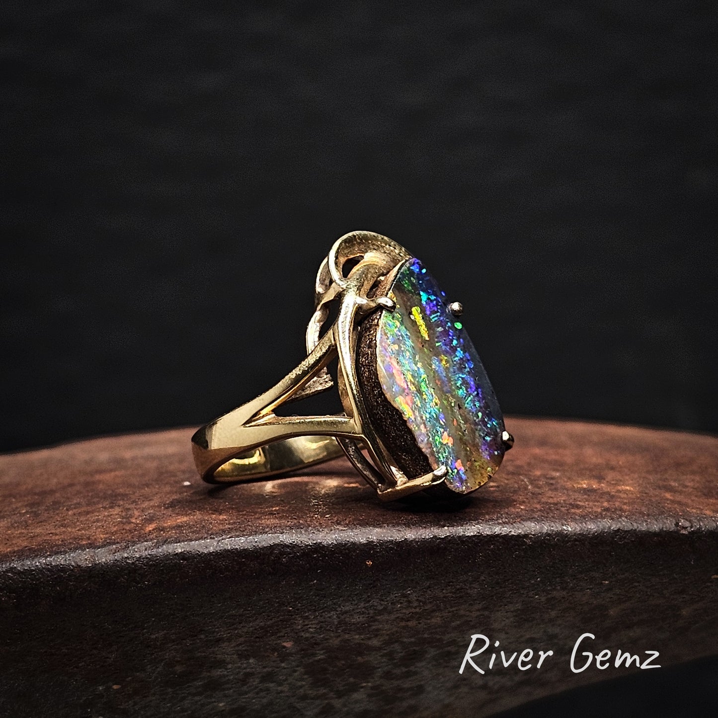 Large free-form cut multi-coloured opal claw set in yellow gold ring.