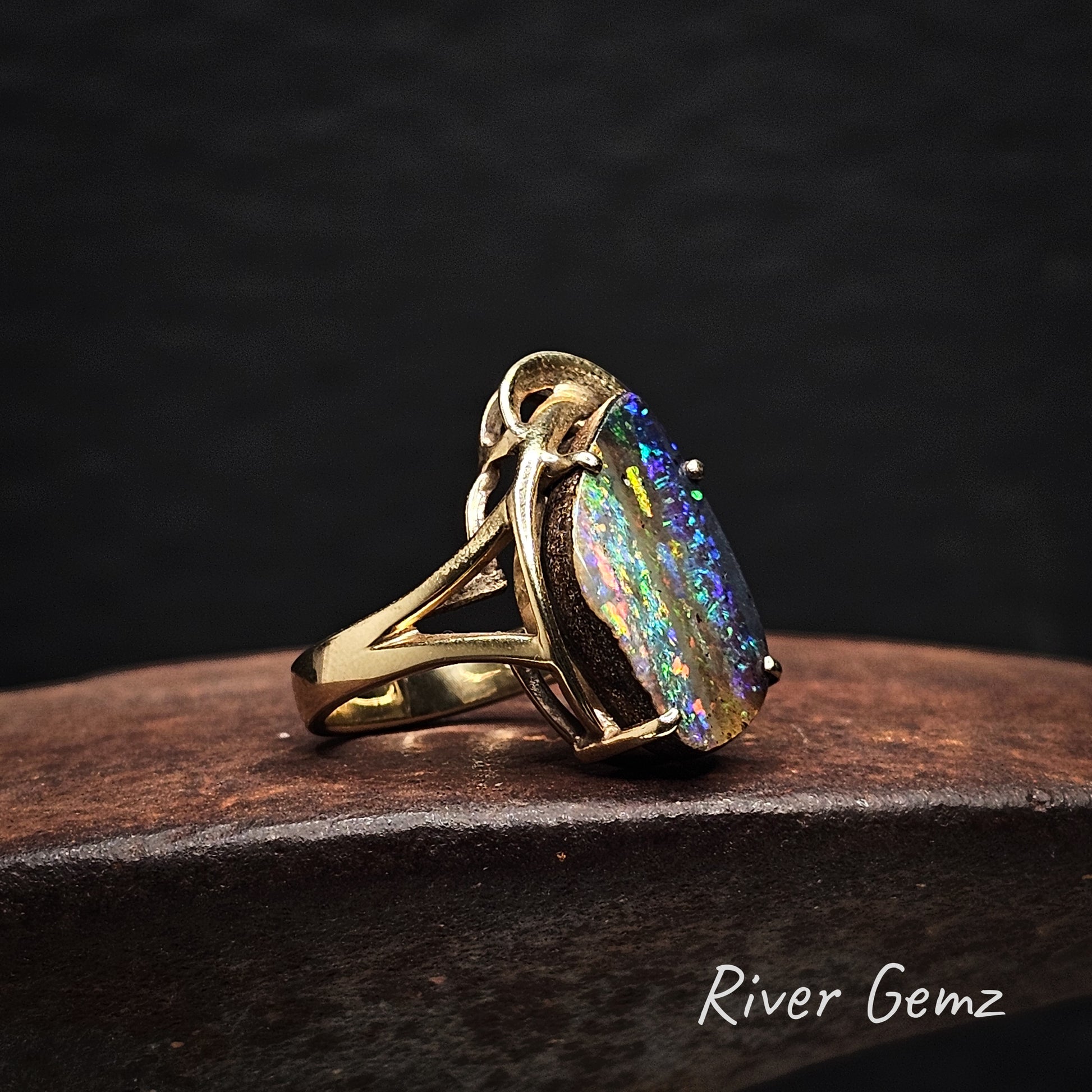 Large free-form cut multi-coloured opal claw set in yellow gold ring.