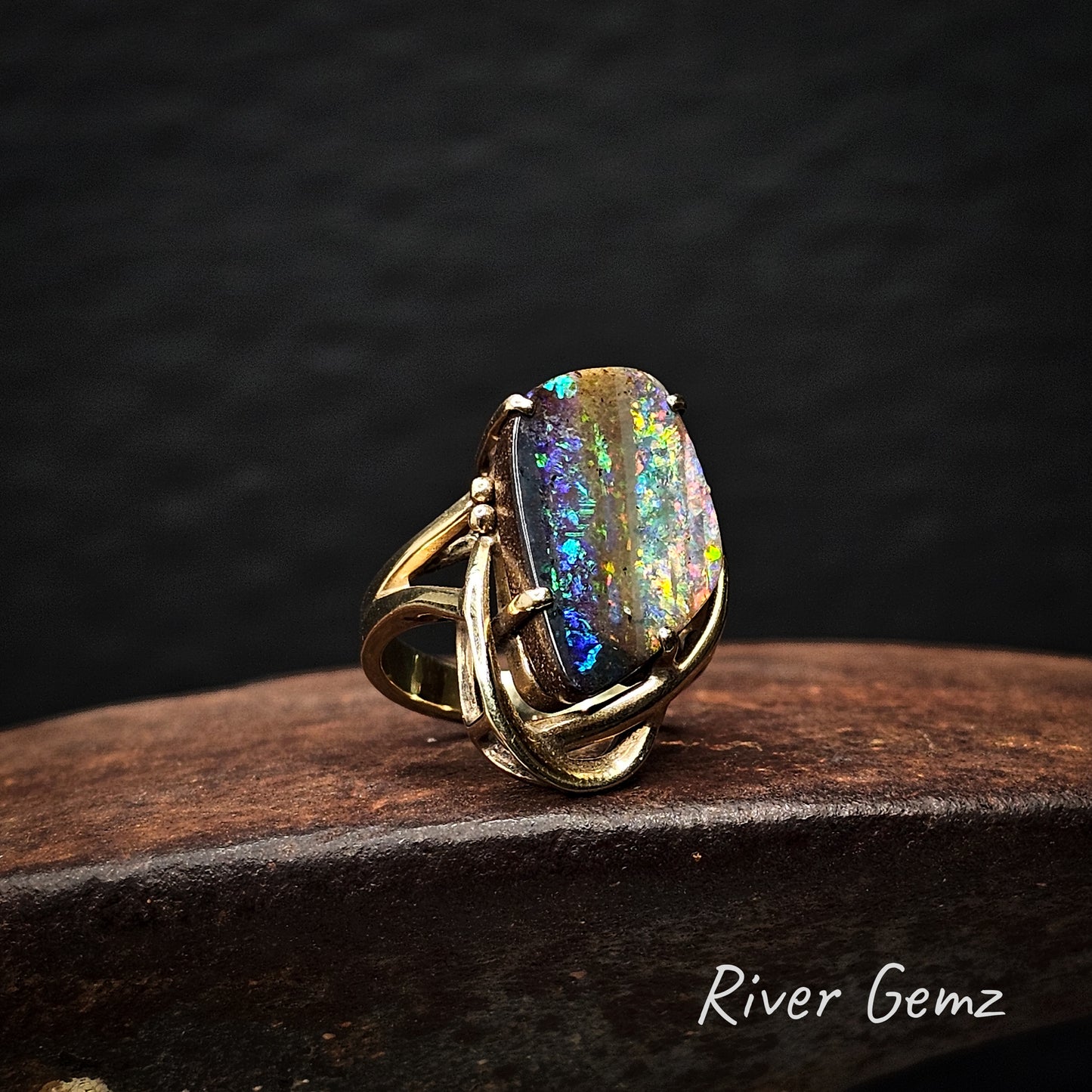 Striped colourations in a large boulder opal set in a gold ring.
