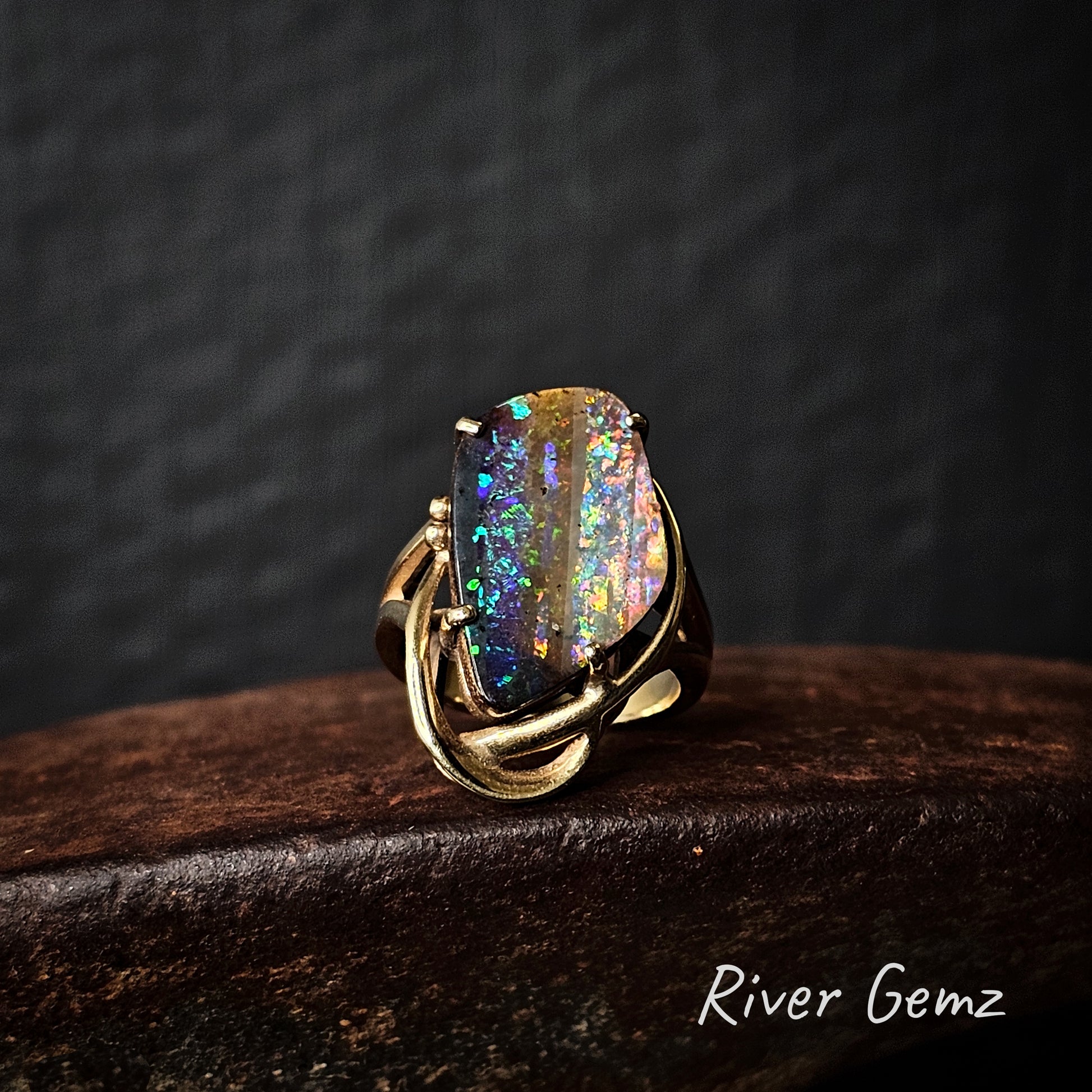 4-sided boulder opal with stripe pattern of various colours set in a yellow gold ring.