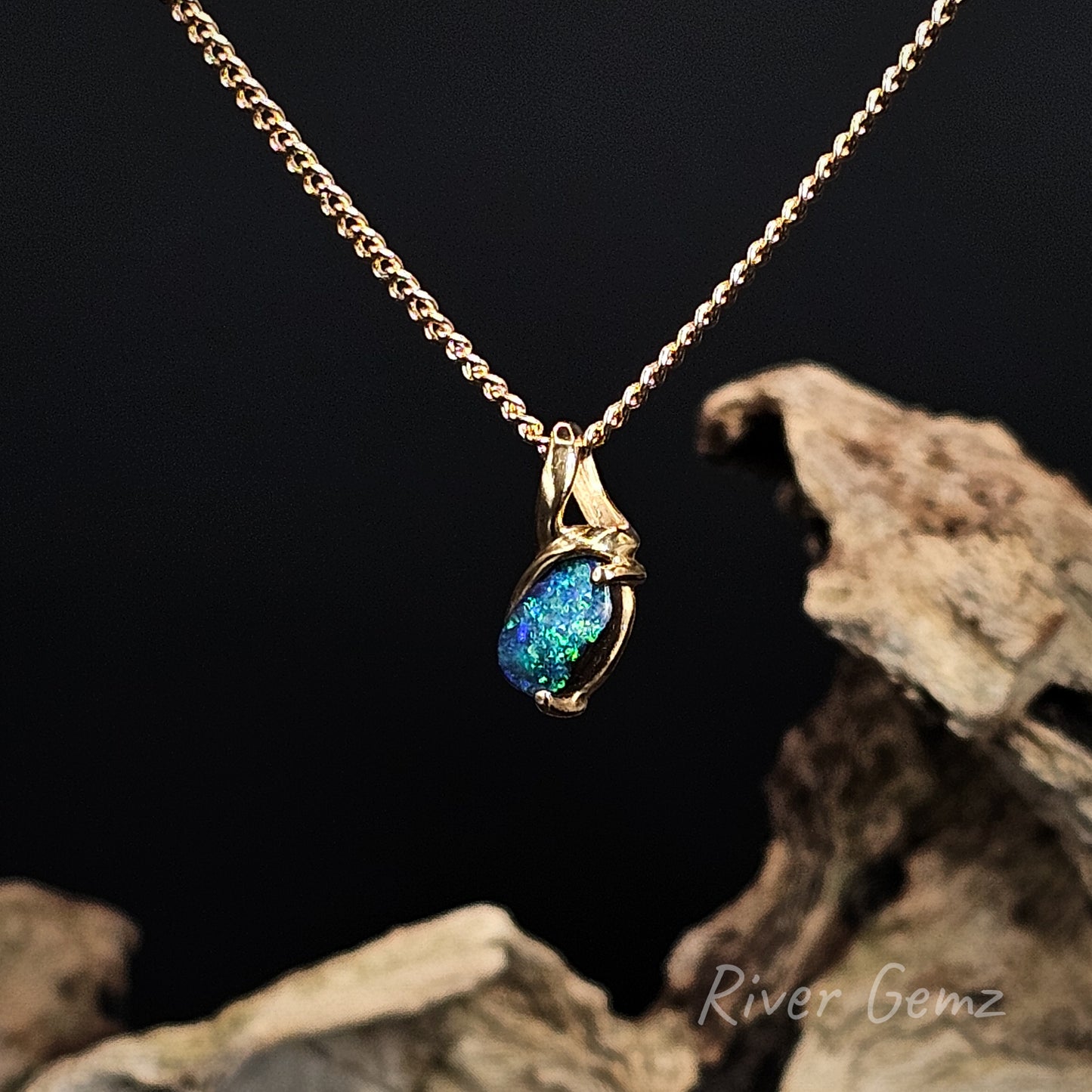 Gold necklace with a blue gemstone pendant on a dark background