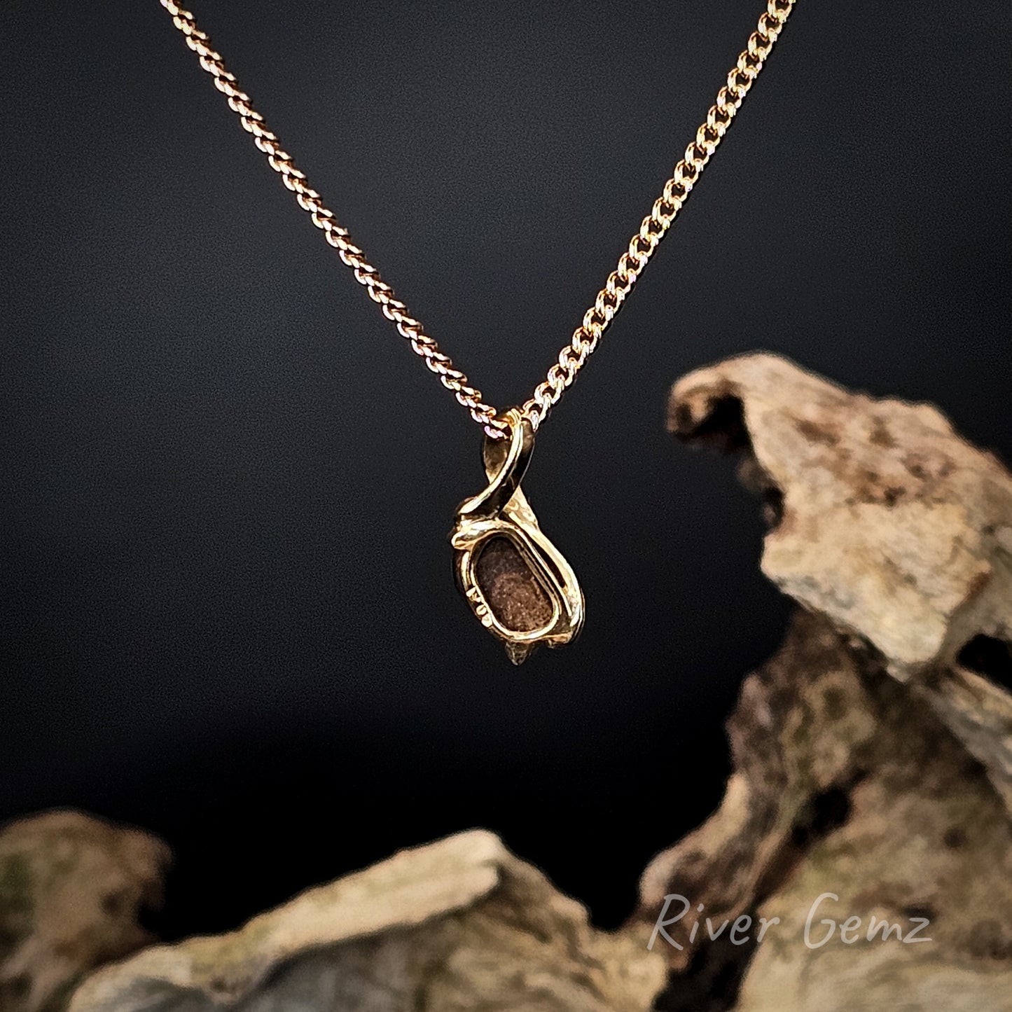 Rear view shows the ironstone matrix of the boulder opal in the gold necklace on a dark background