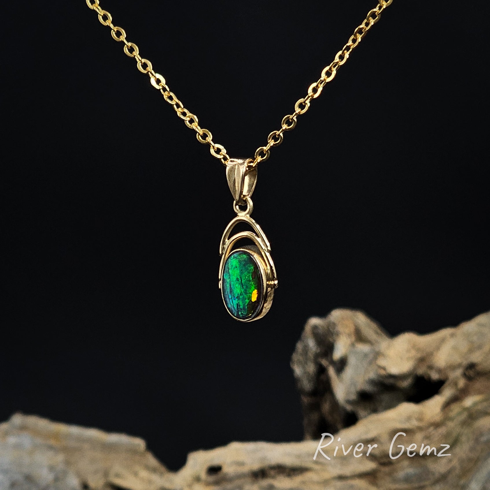 Gold necklace with a green boulder opal pendant on a dark background