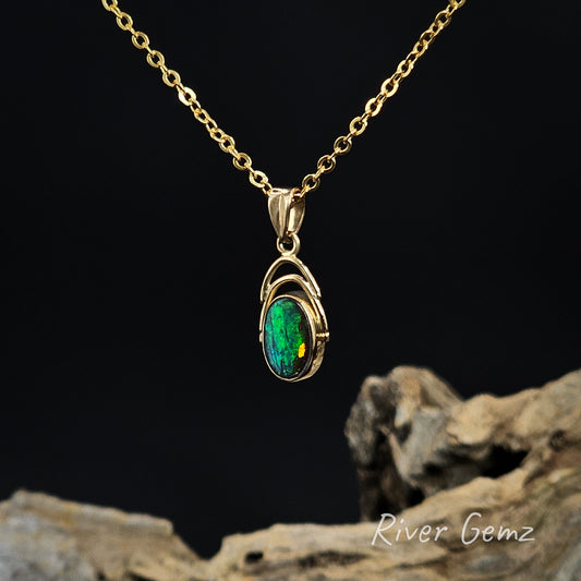 Gold necklace with a green boulder opal pendant on a dark background