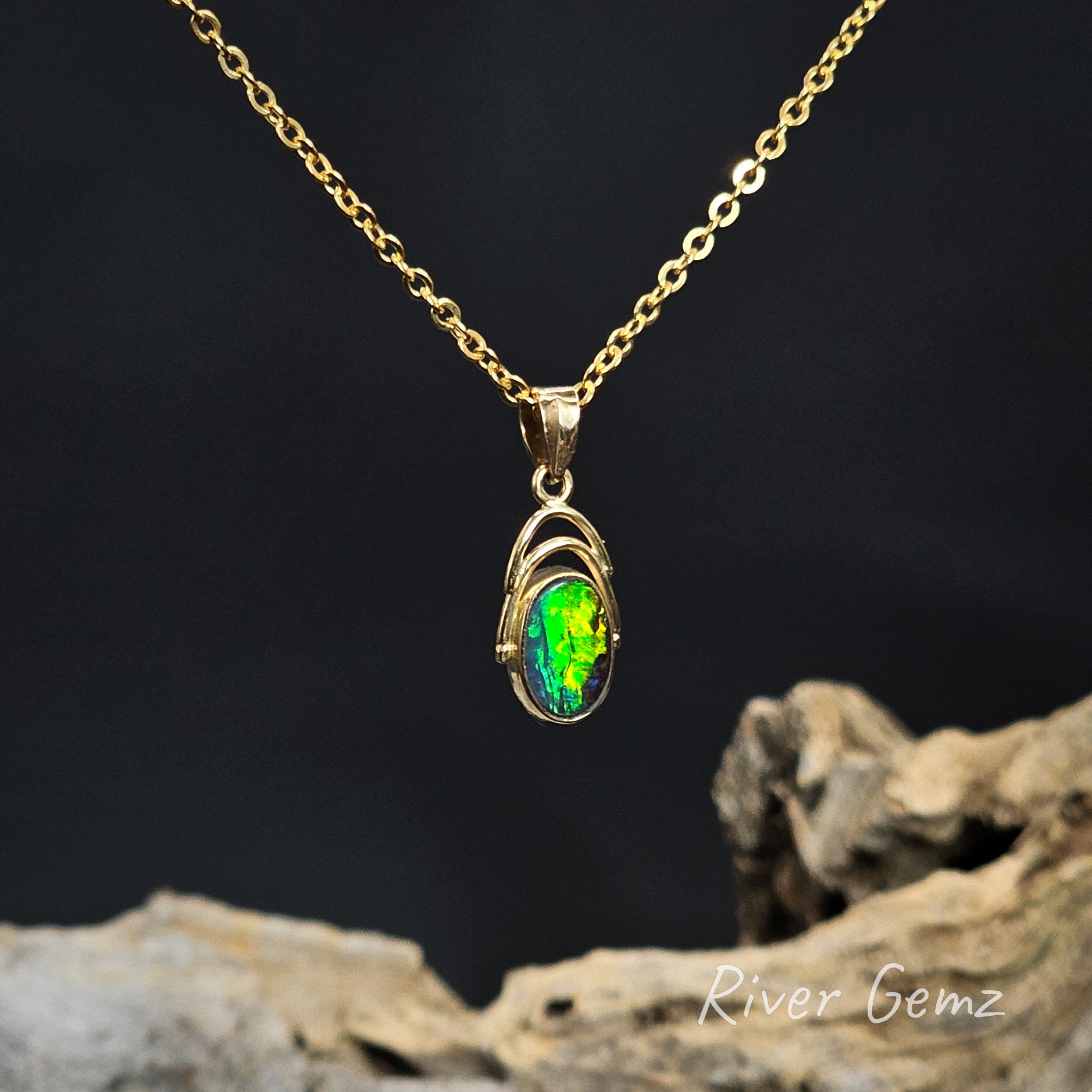 Gold necklace with an oval-shaped vibrant green boulder opal pendant on a dark background
