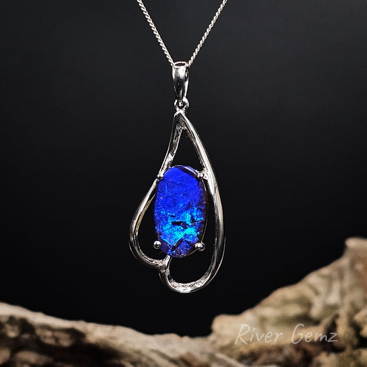 White gold pendant with a blue boulder opal on a dark background