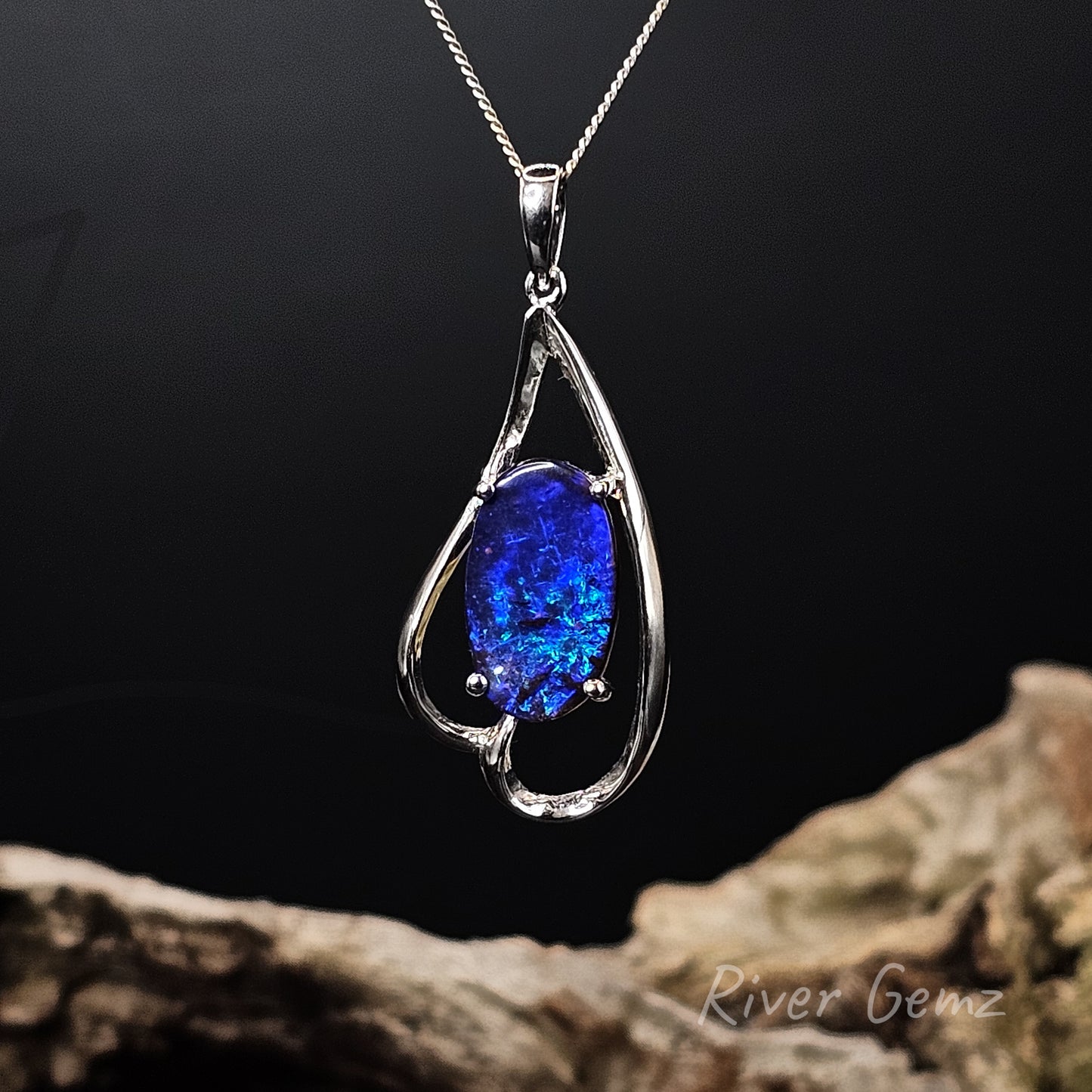White gold pendant with a blue gemstone on a dark background