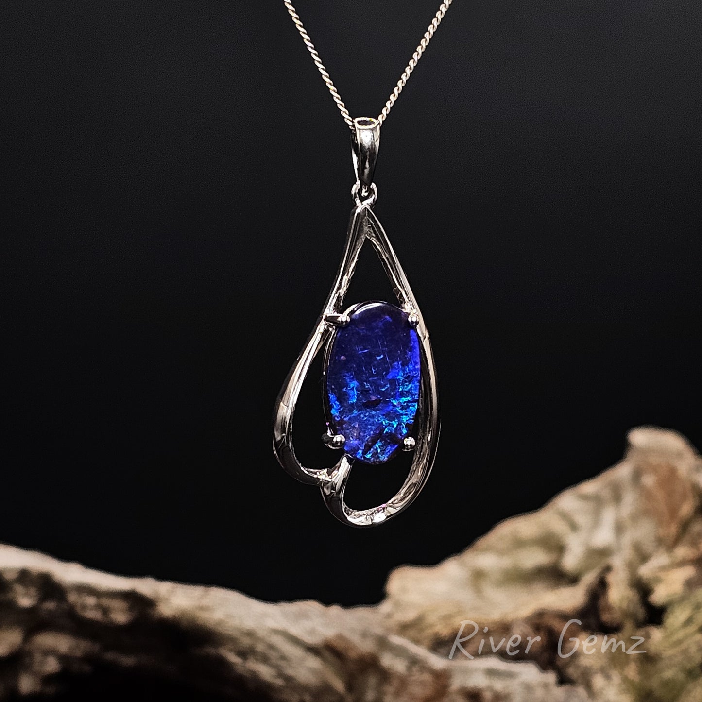 White gold pendant with a blue gemstone on a dark background