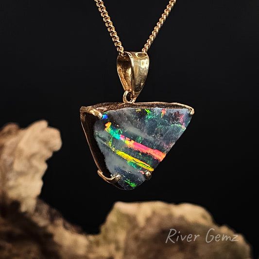 Vibrant coloured boulder opal necklace set in yellow gold on a dark background with 'River Gemz' branding.