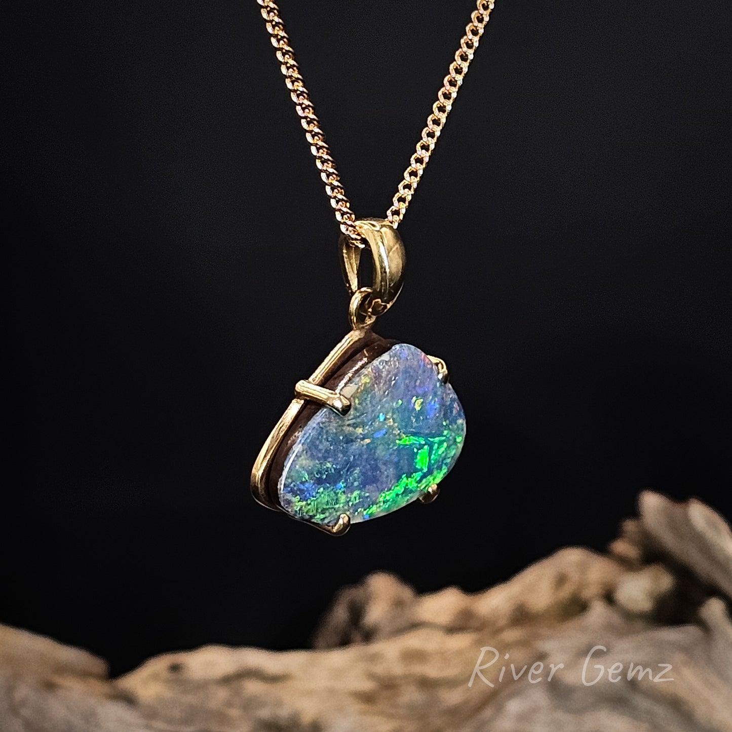 Opal pendant necklace on a gold chain with a dark background.