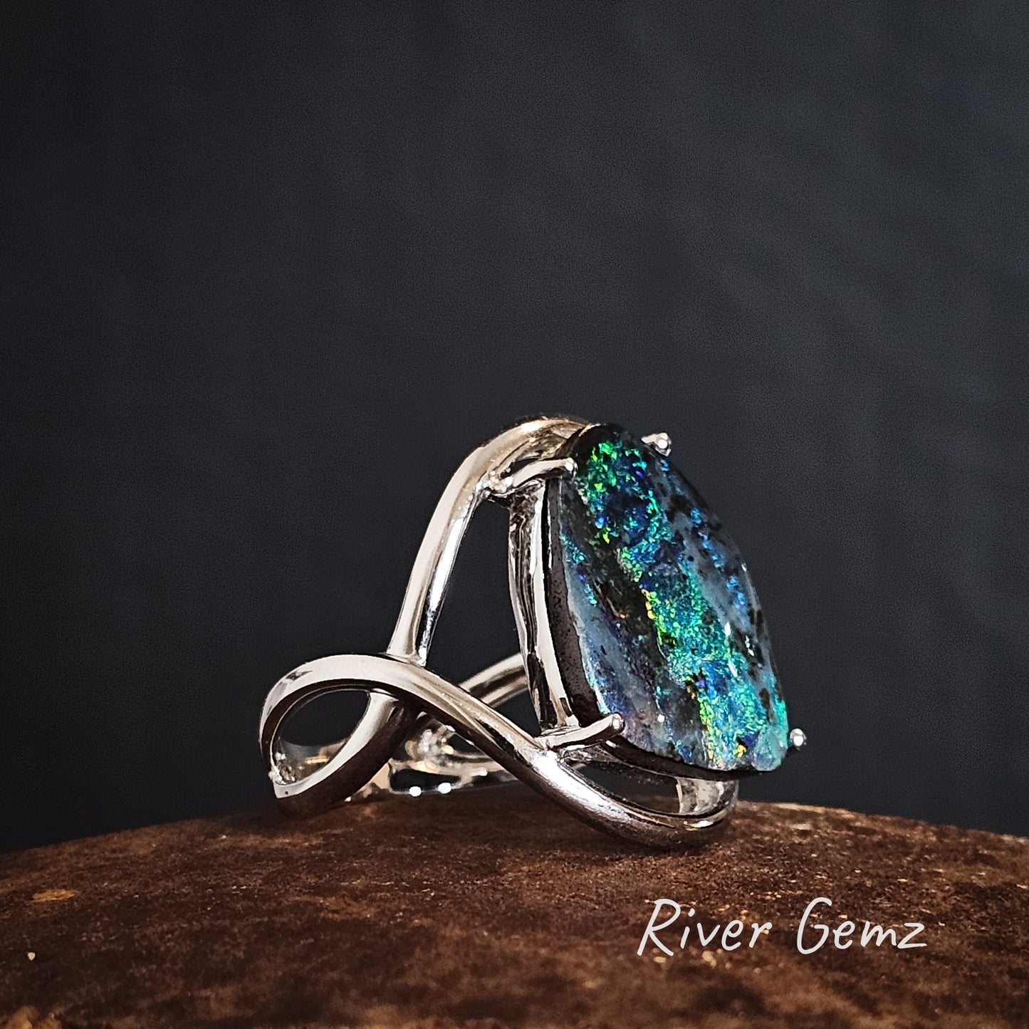 Side view of the white gold ring with a blue and green opal on a dark background, branded 'River Gemz'.