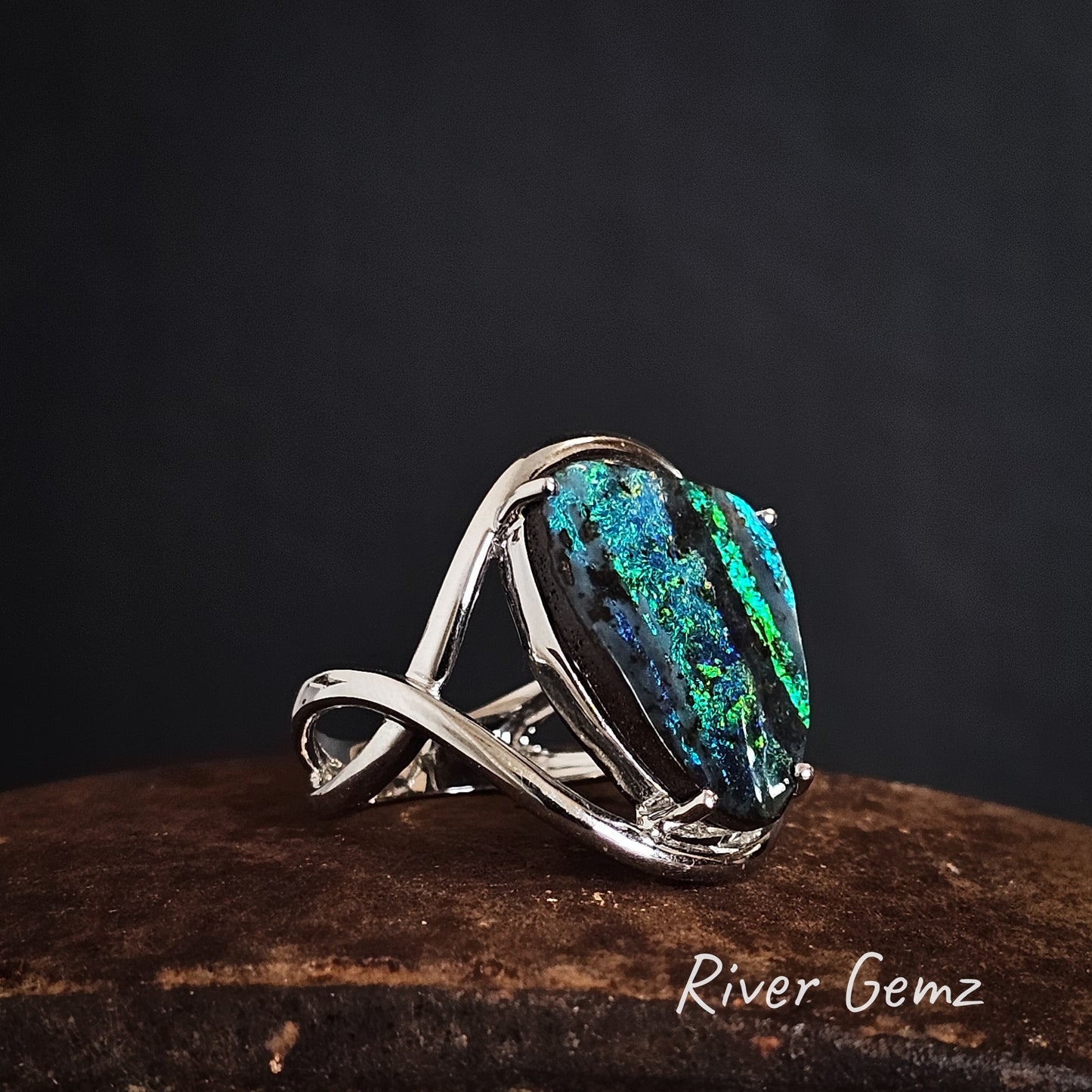White gold ring with a striped boulder opal on a dark background, branded 'River Gemz'.
