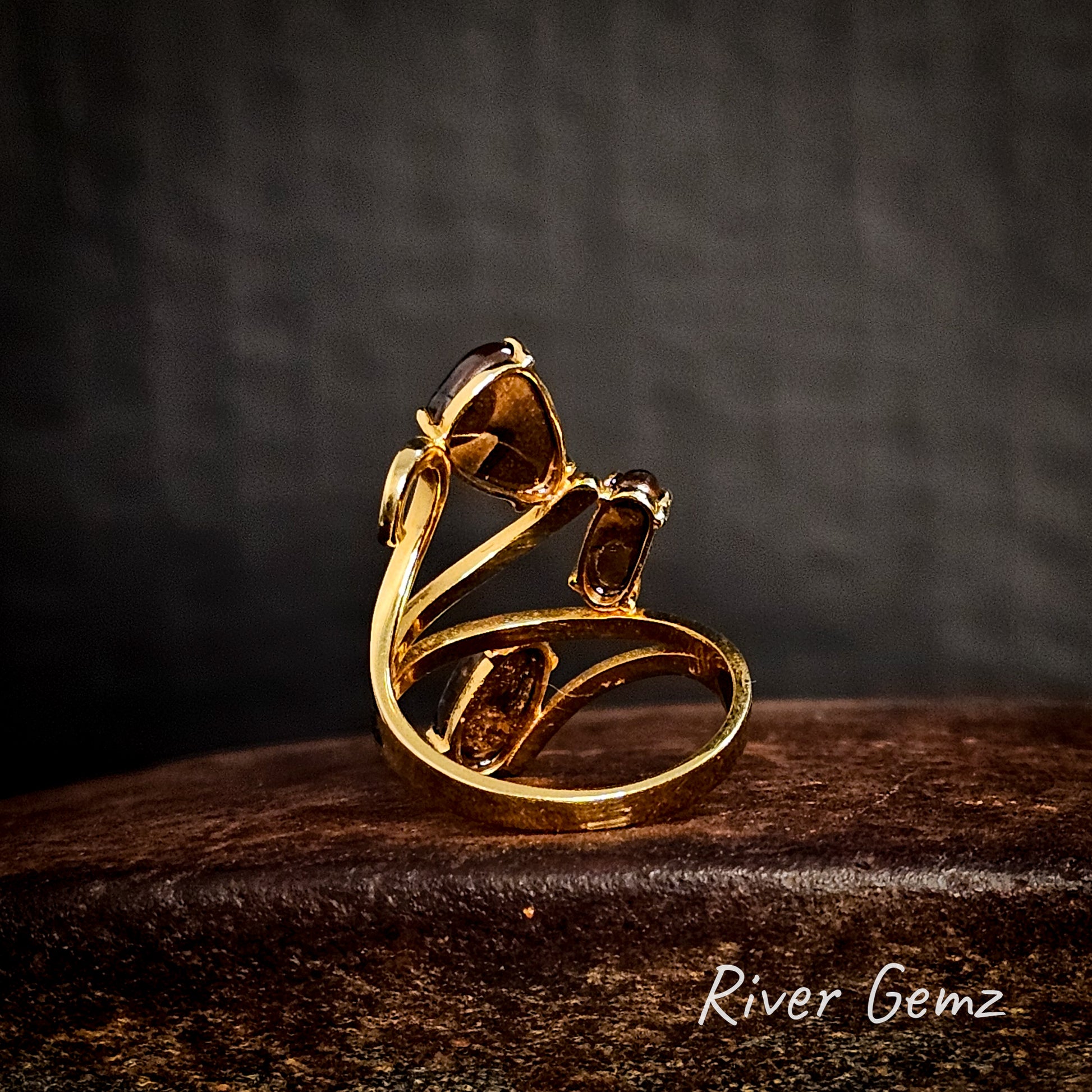 Back of gold ring showing the ironstone matrix of the 3 boulder opals on a cast iron surface, branded 'River Gemz'.