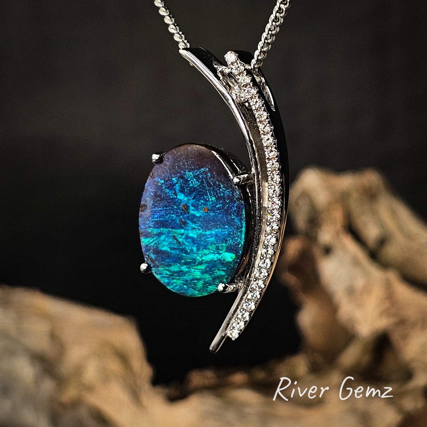Blue and green opal and diamond pendant set in white gold on a dark background.