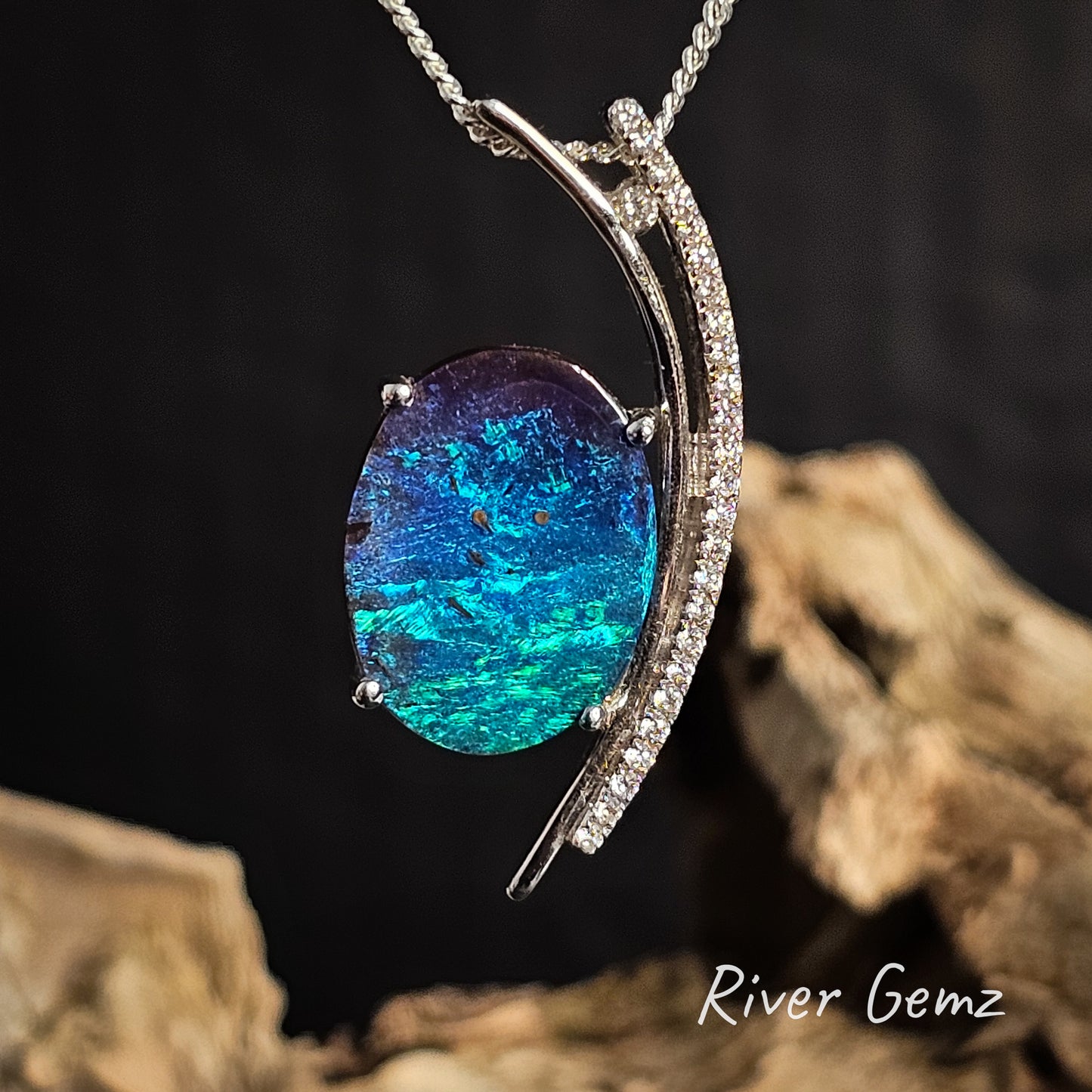 Oval shaped boulder opal pendant necklace with 'River Gemz' branding on a dark background.