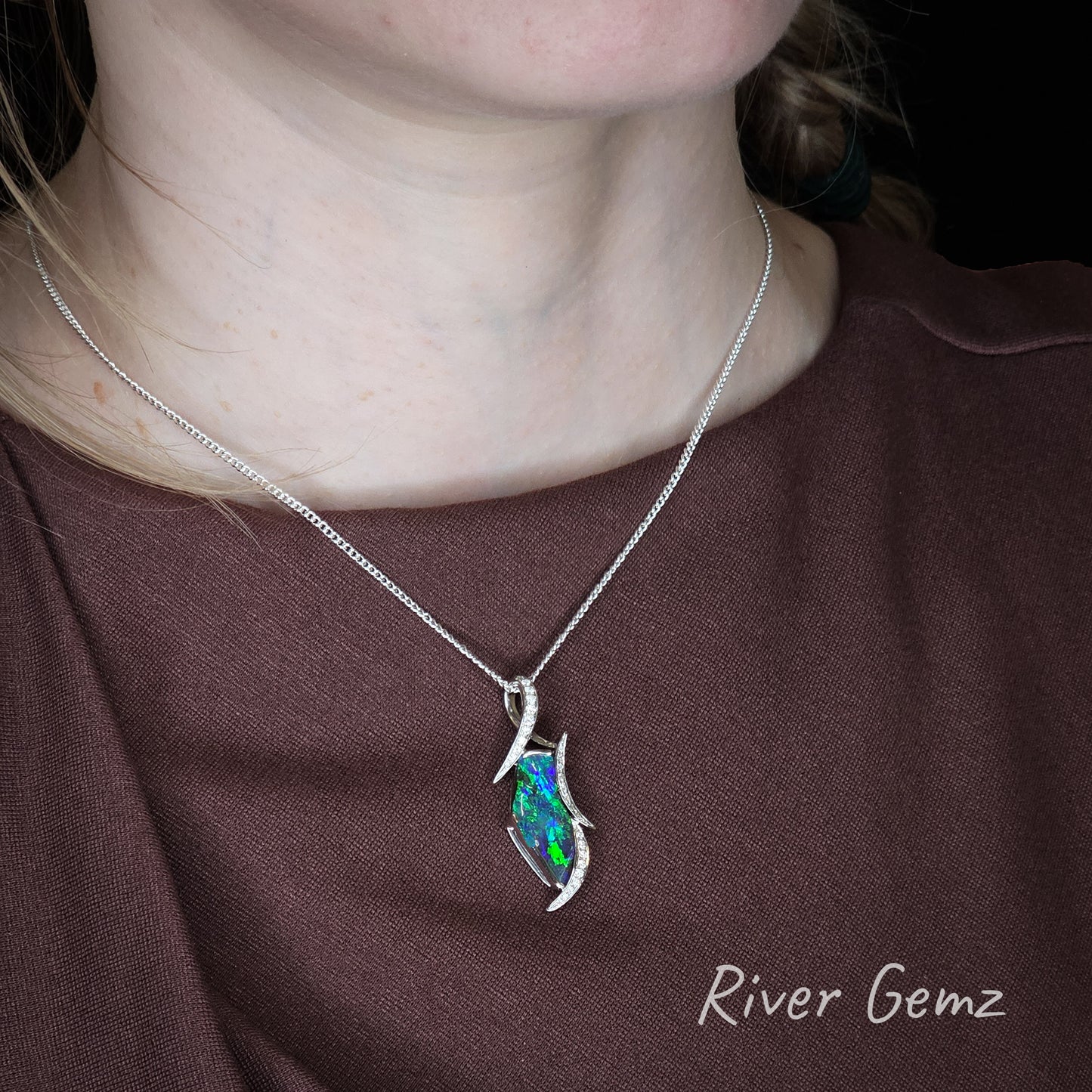 Necklace with a colorful pendant worn by a person, brand 'River Gemz' visible.
