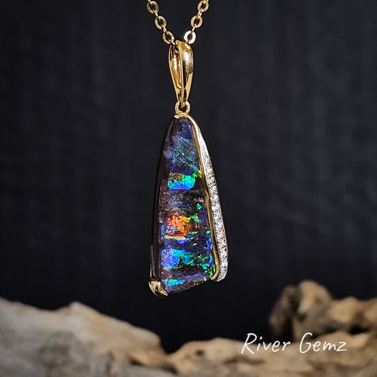 Colourful boulder opal and pave set diamonds necklace with gold chain on a dark background, featuring the brand 'River Gemz'.