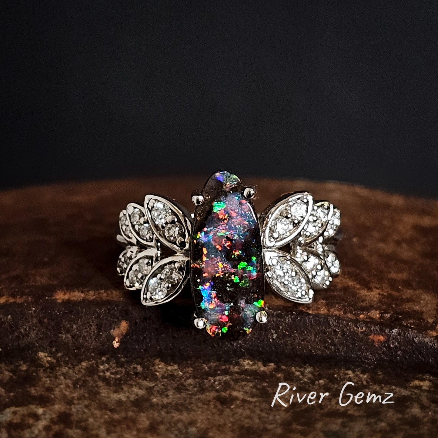 Boulder opal ring with diamond leaf designs on a dark background, branded 'River Gemz'.