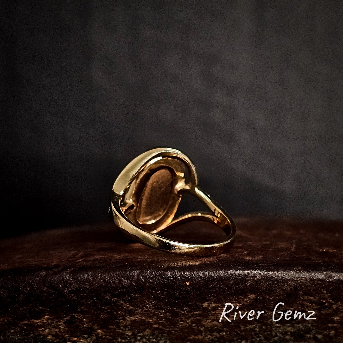 Rear view of the gold ring showing the brown base colour of the boulder opal on a dark surface with 'River Gemz' branding.