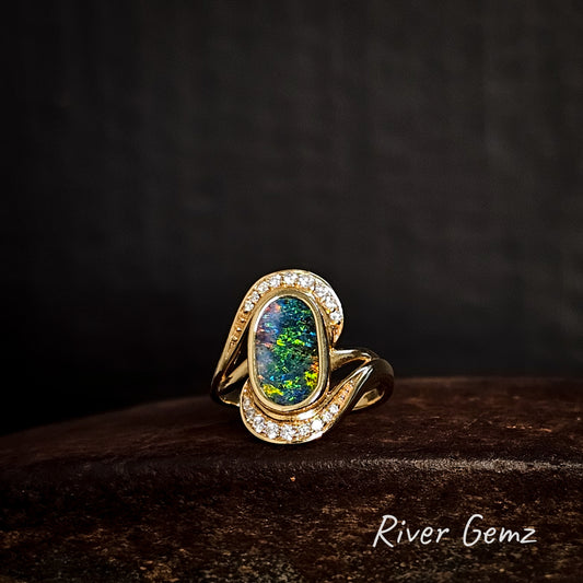 Gold ring with a multi-coloured boulder opal and diamonds on a dark background, featuring the brand 'River Gemz'.