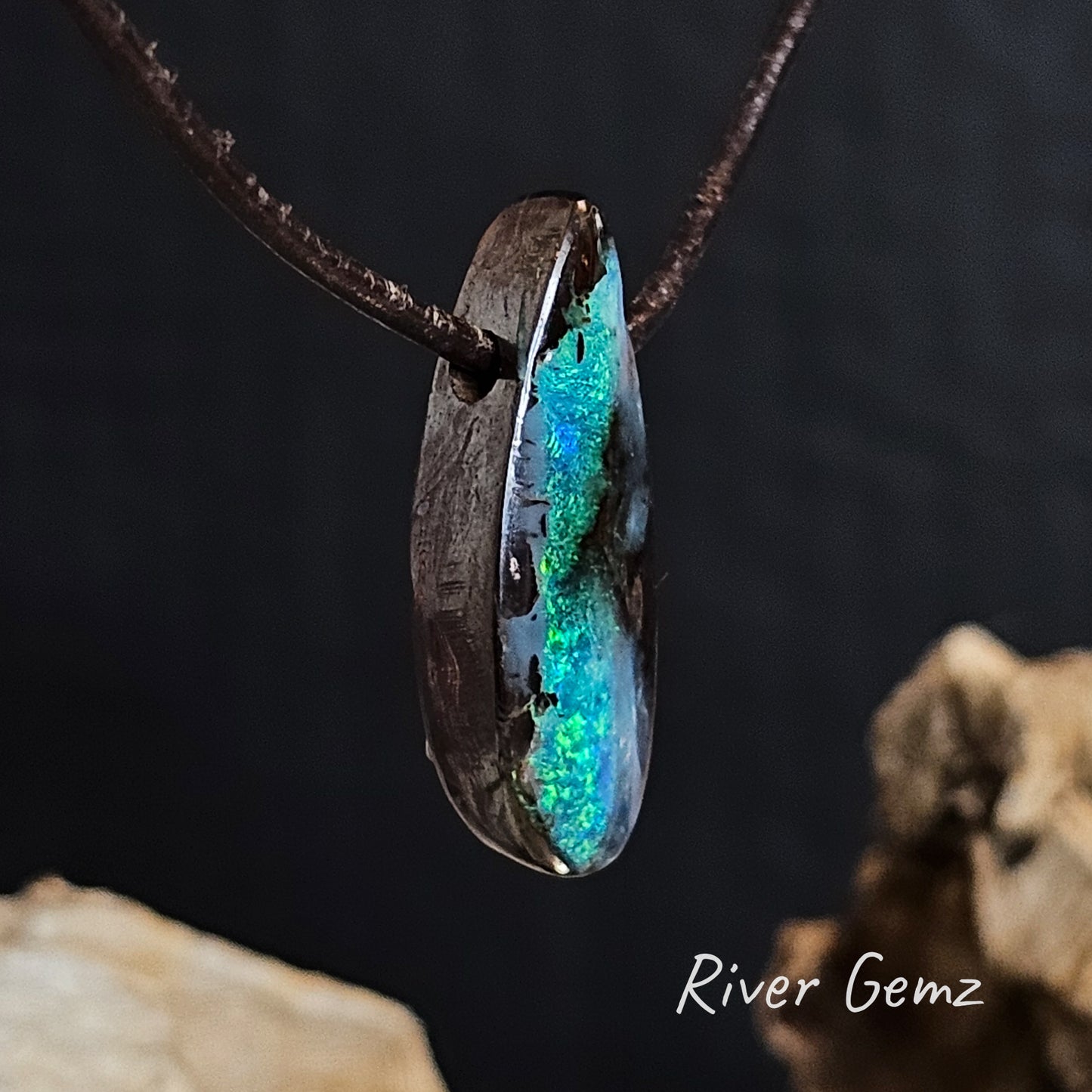 Side view shows the thickness of the boulder opal and the drilled hole through which the leather of the necklace passes.