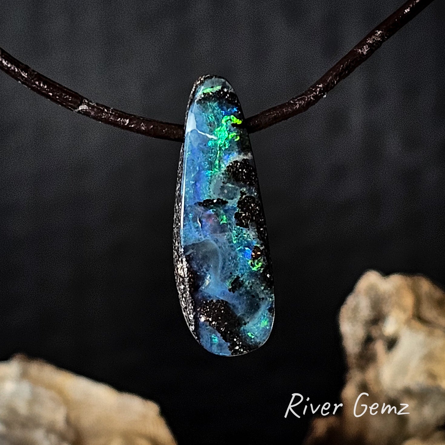 Boulder opal on leather pendant on a dark background with 'River Gemz' branding.