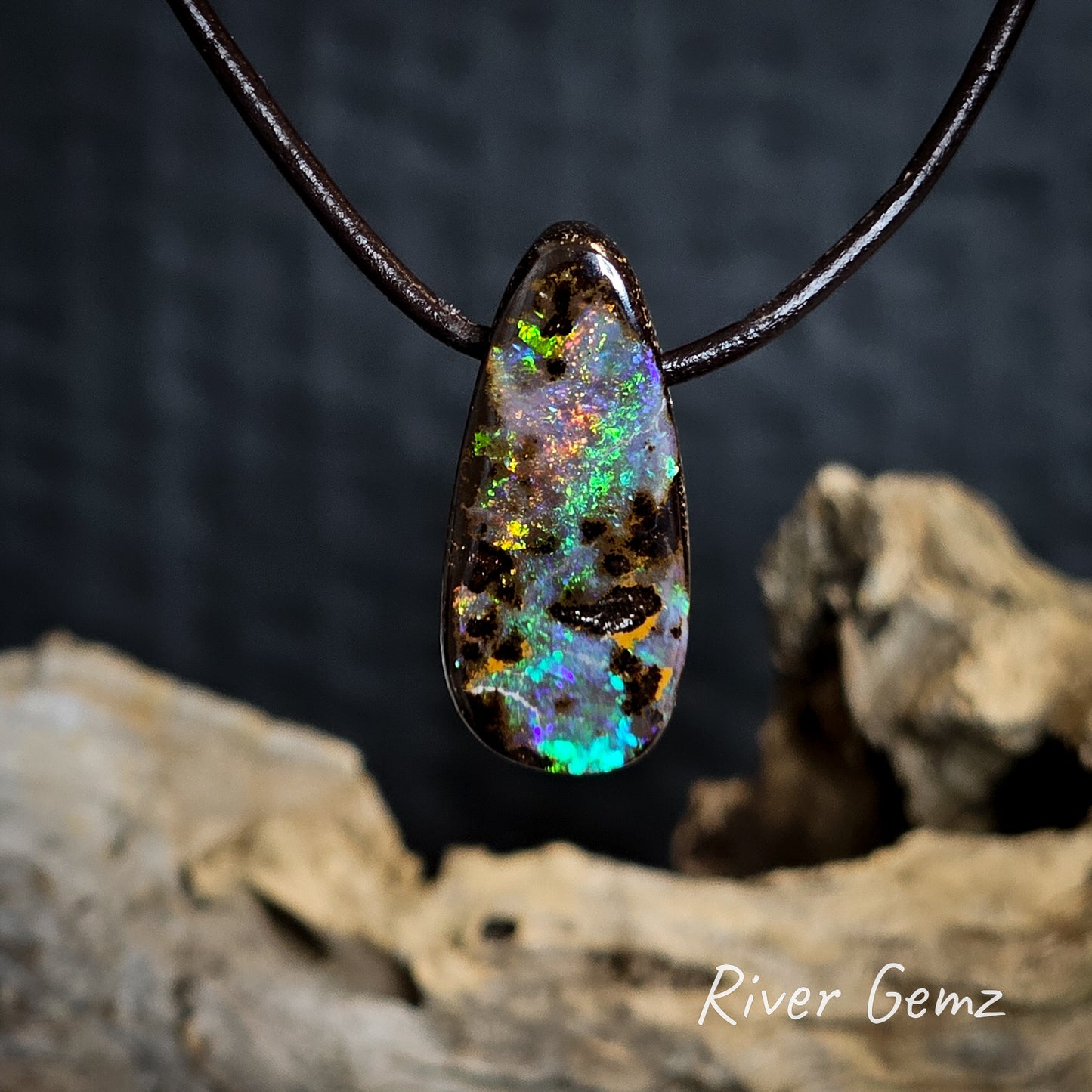 Multi-coloured boulder opal pendant on a dark background with 'River Gemz' branding.
