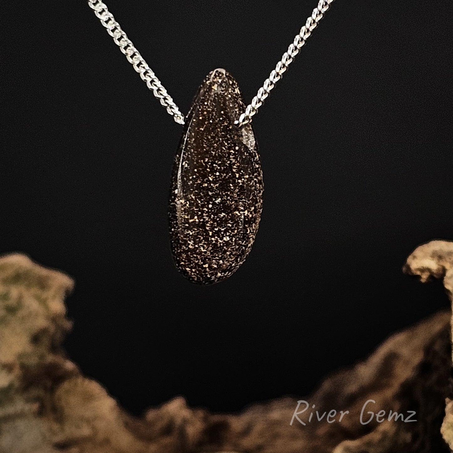 Rear view of pendant showing the speckled brown surface of the boulder opal on a chain against a dark background with 'River Gemz' branding.
