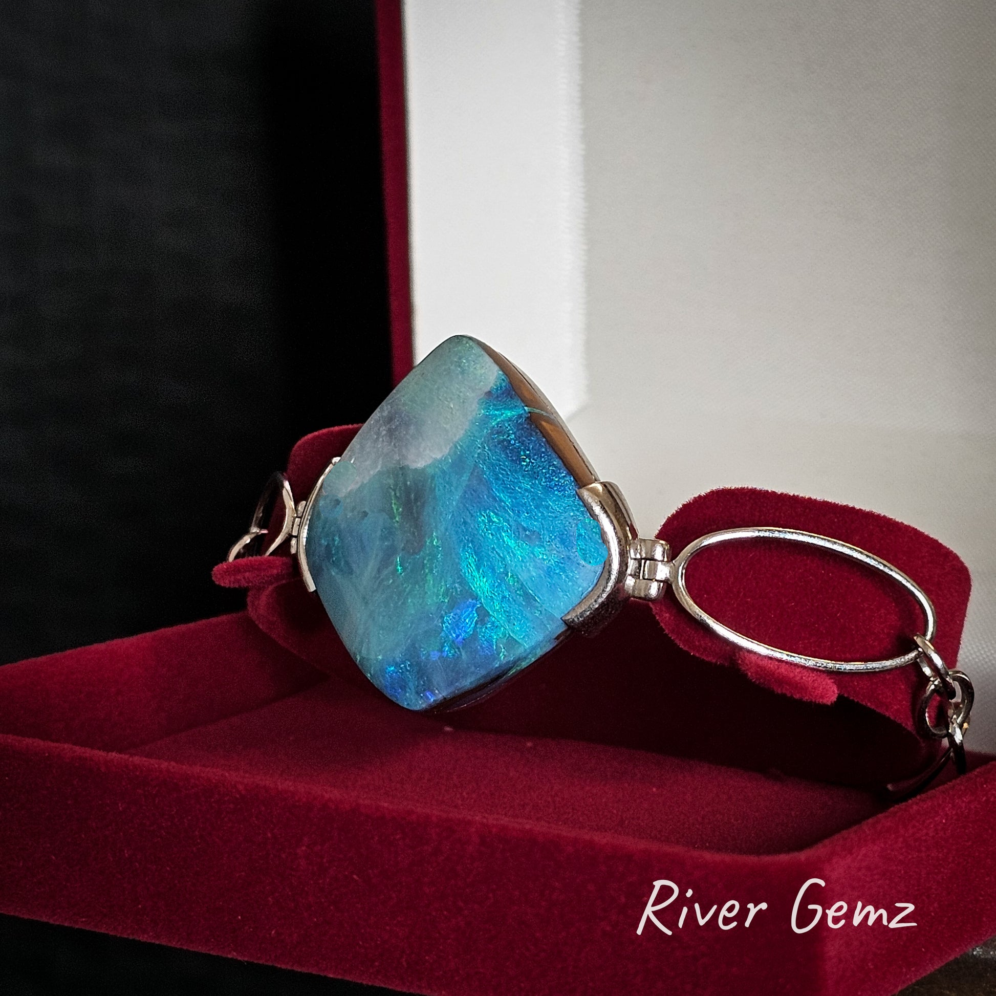 Blue and green gemstone bracelet in a velvet jewellery box with 'River Gemz' branding.