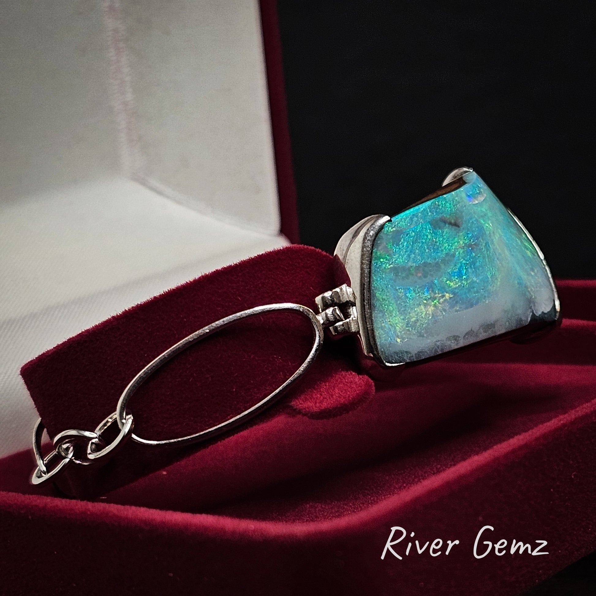 Opal bracelet with silver chain links in a red jewellery box, 'River Gemz' brand visible.