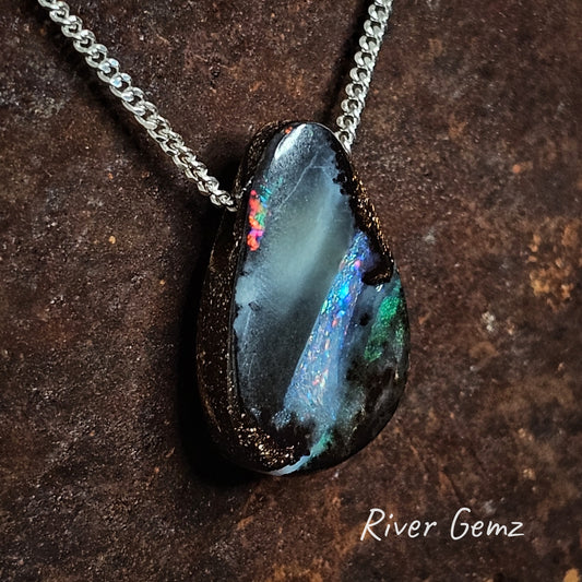 Dark teardrop shaped opal with unusual colouration on a silver chain.