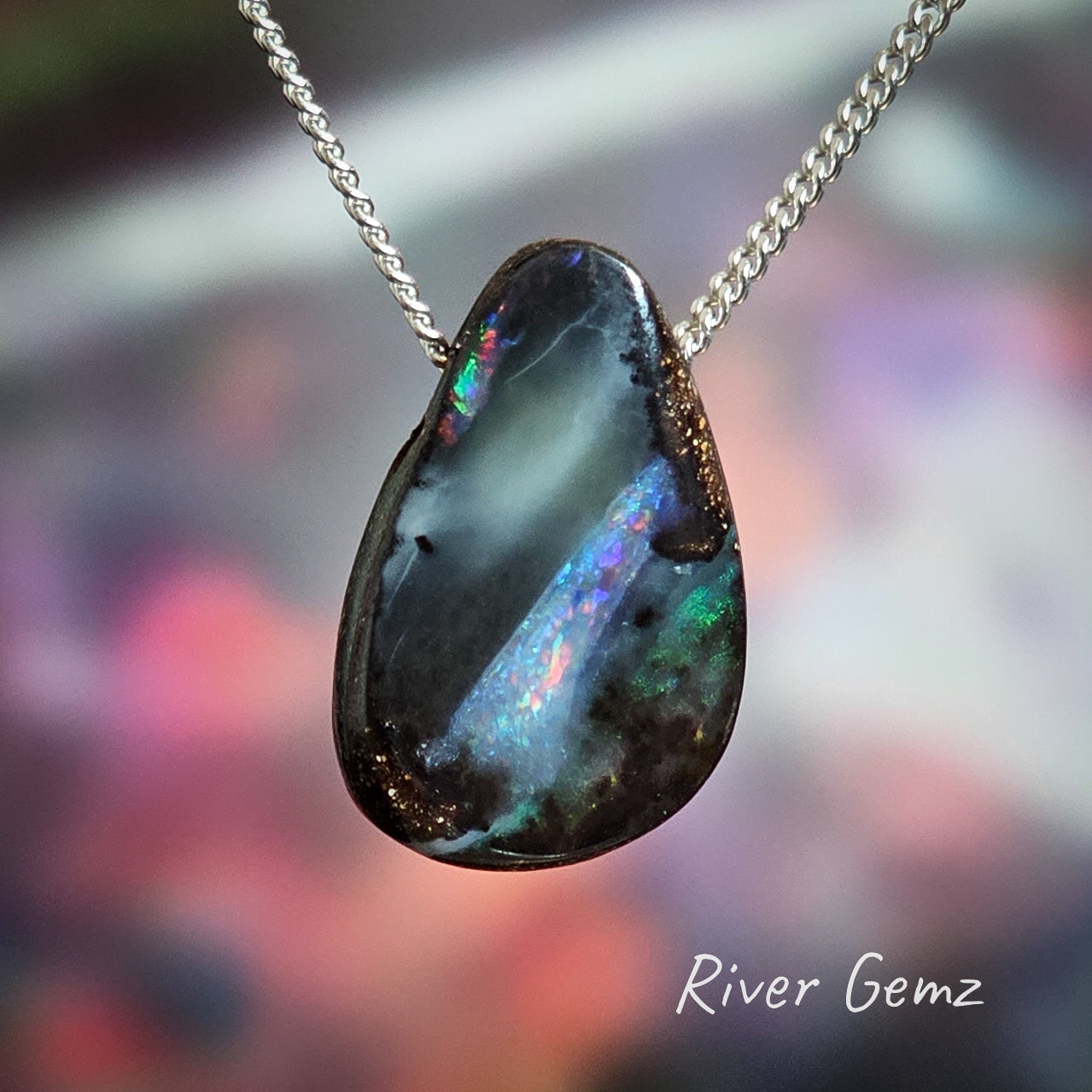 Boulder opal with a black smokey background to the coloured stripes on a sterling silver necklace.