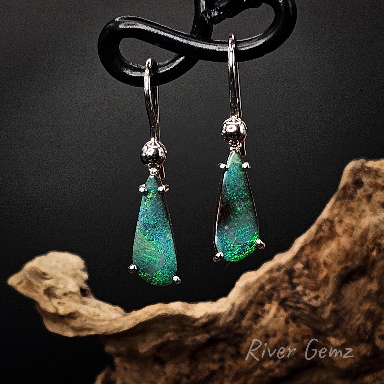 Tear drop shaped dark green boulder opals claw set in silver hooks.