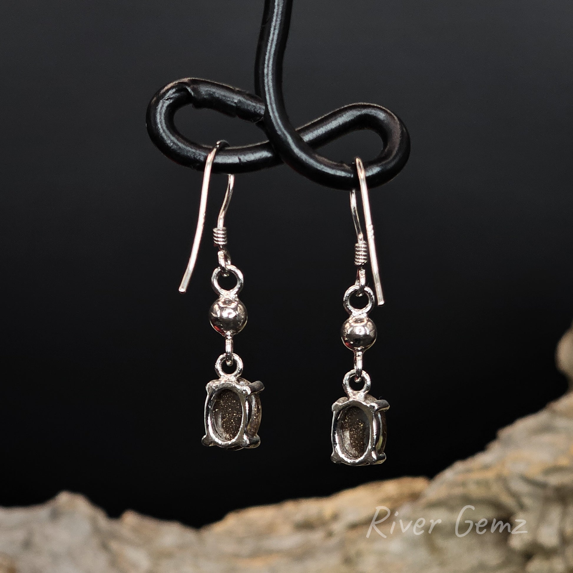 Rear view of silver earrings shows the brown ironstone base of the boulder opals set within them.