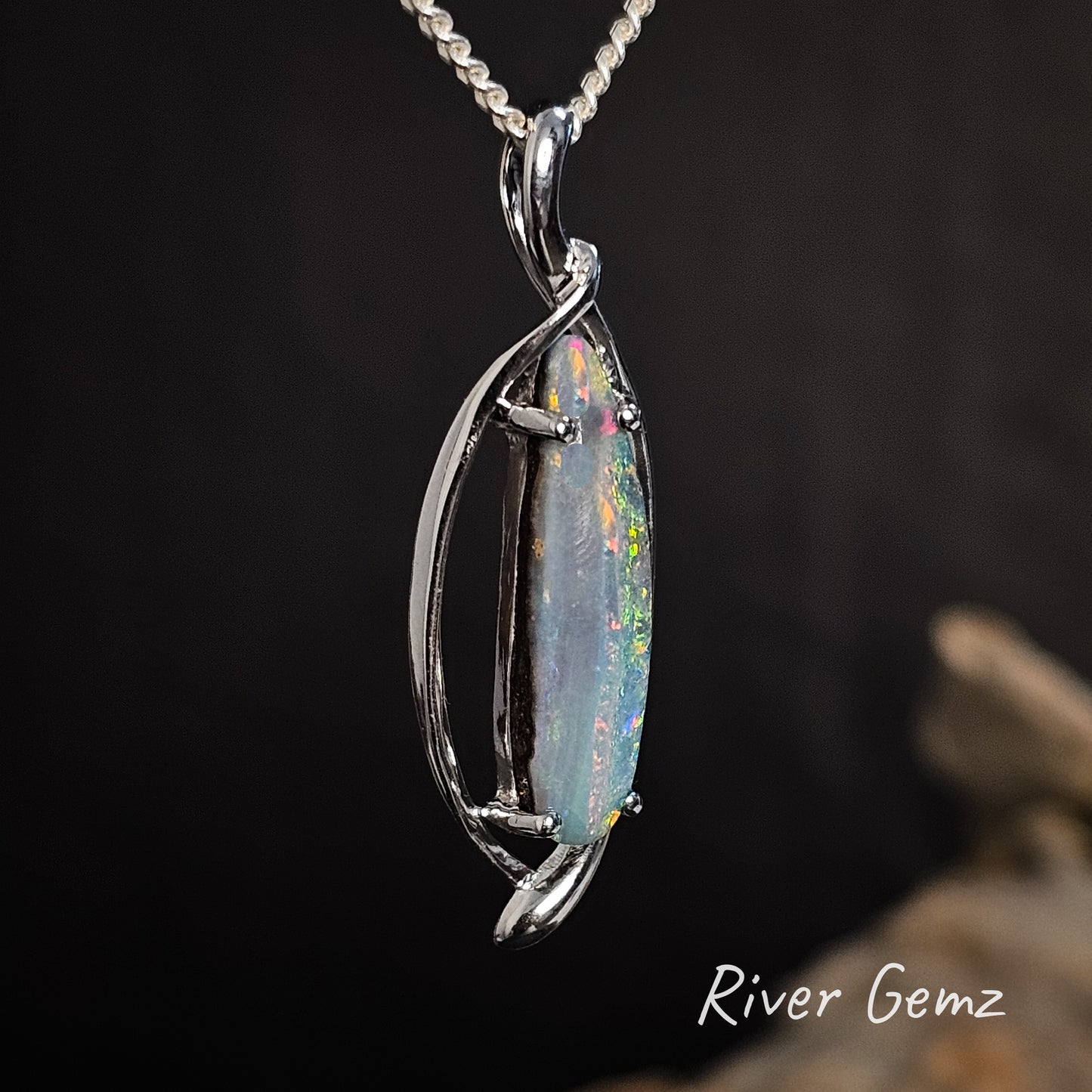 Side view of the sterling silver necklace shows the colourful stripes of the boulder opal.