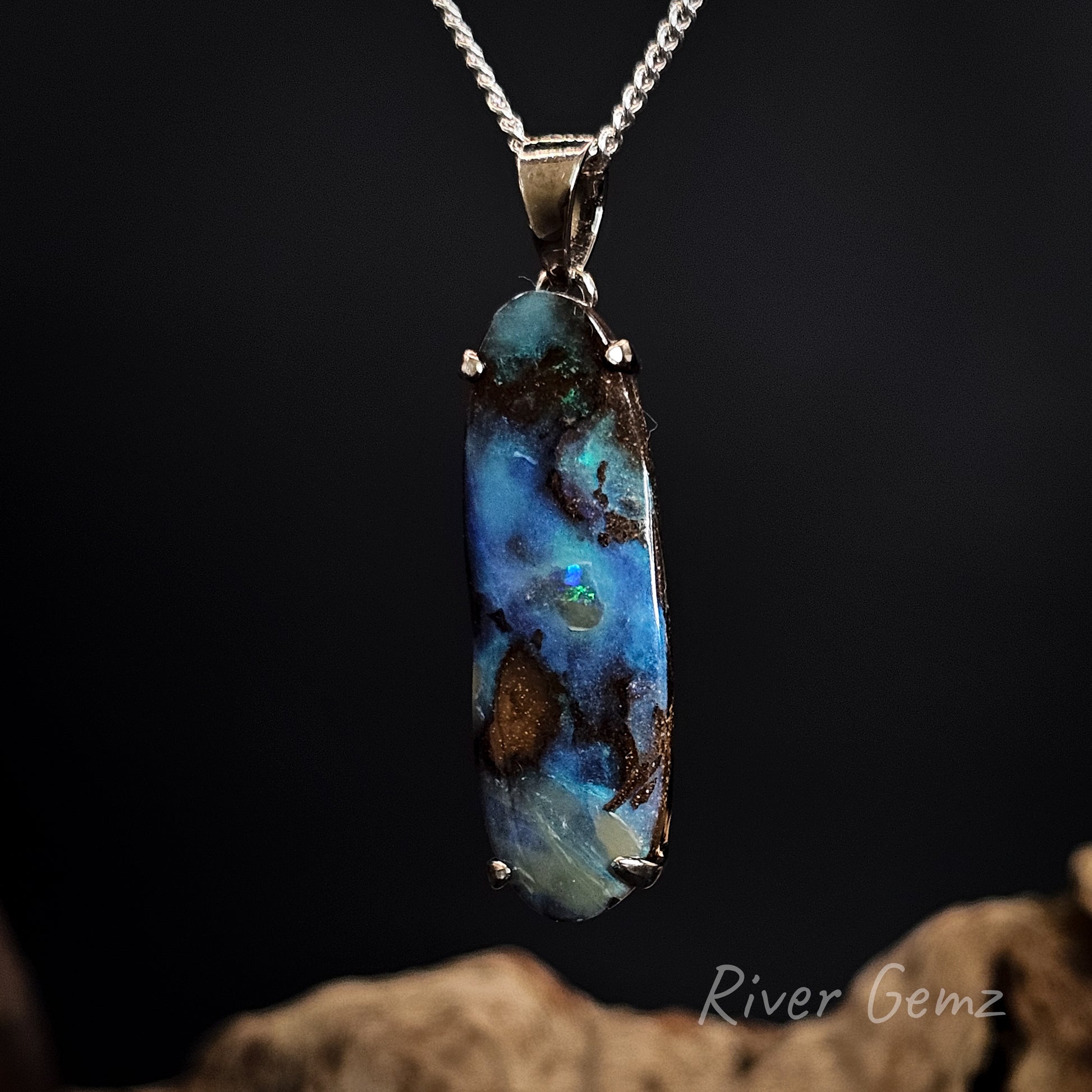Blue opal pendant on a chain against a dark background