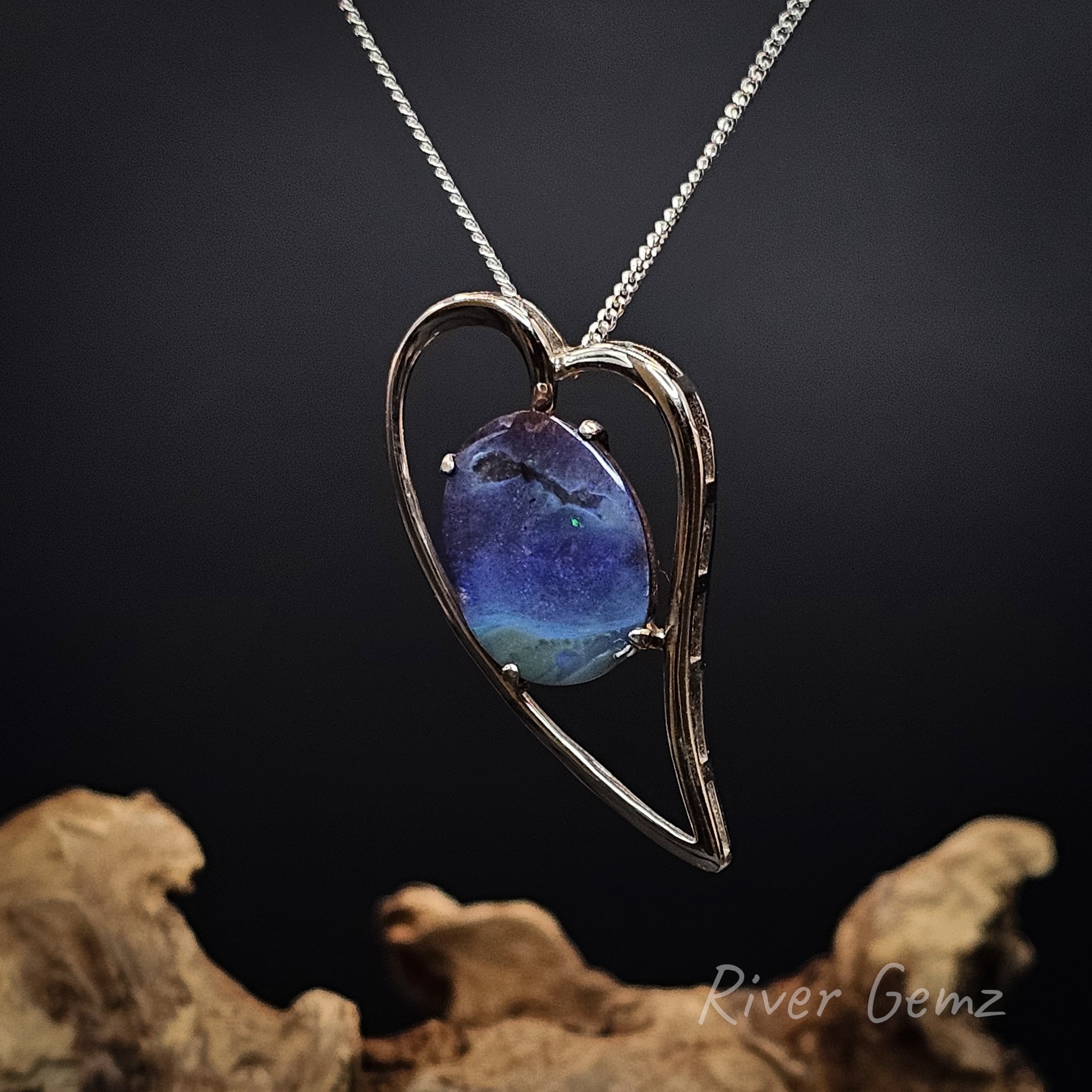 Love heart shaped pendant with an oval shaped boulder opal claw set within the sterling silver setting.