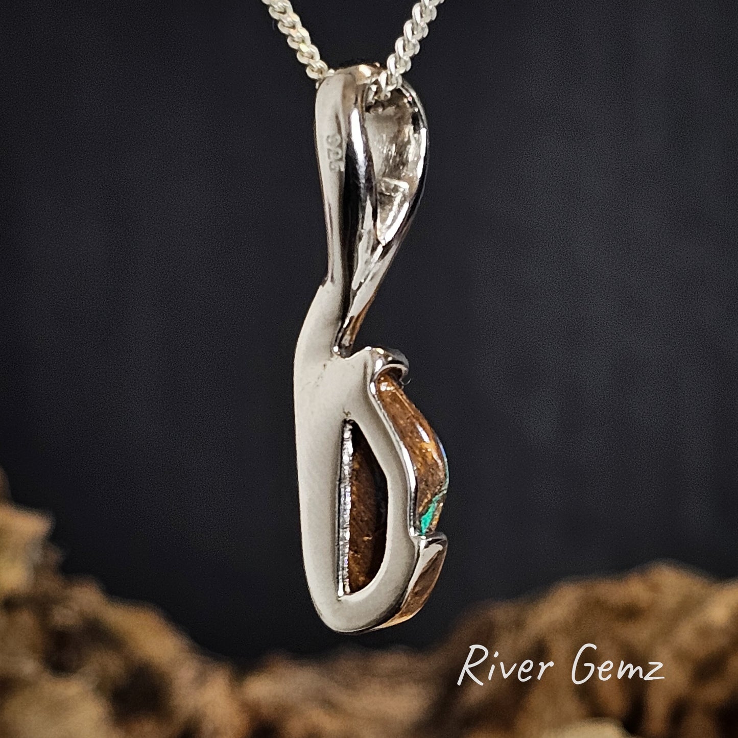 Back of silver pendant showing the ironstone matrix of the boulder opal on a dark background, featuring the brand 'River Gemz'.