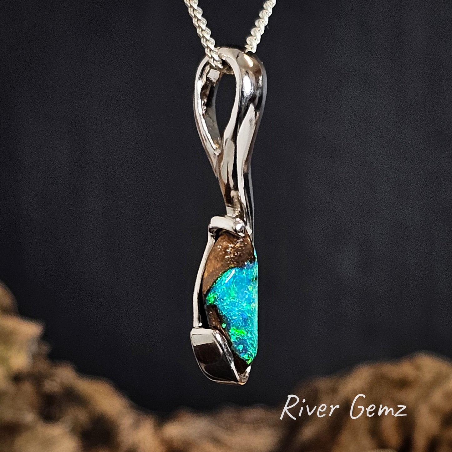 Silver pendant with blue and green boulder opal on a dark background, featuring 'River Gemz' branding.