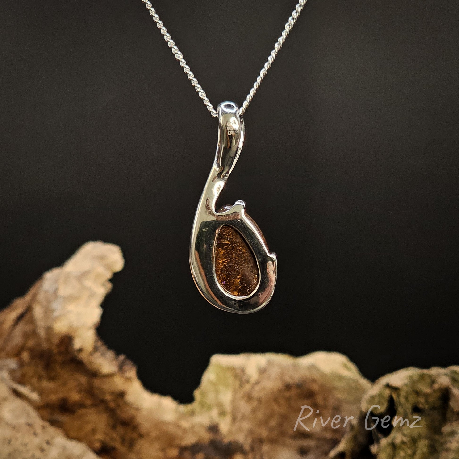 Rear view of the necklace shows the ironstone matrix of the boulder opal on a dark background