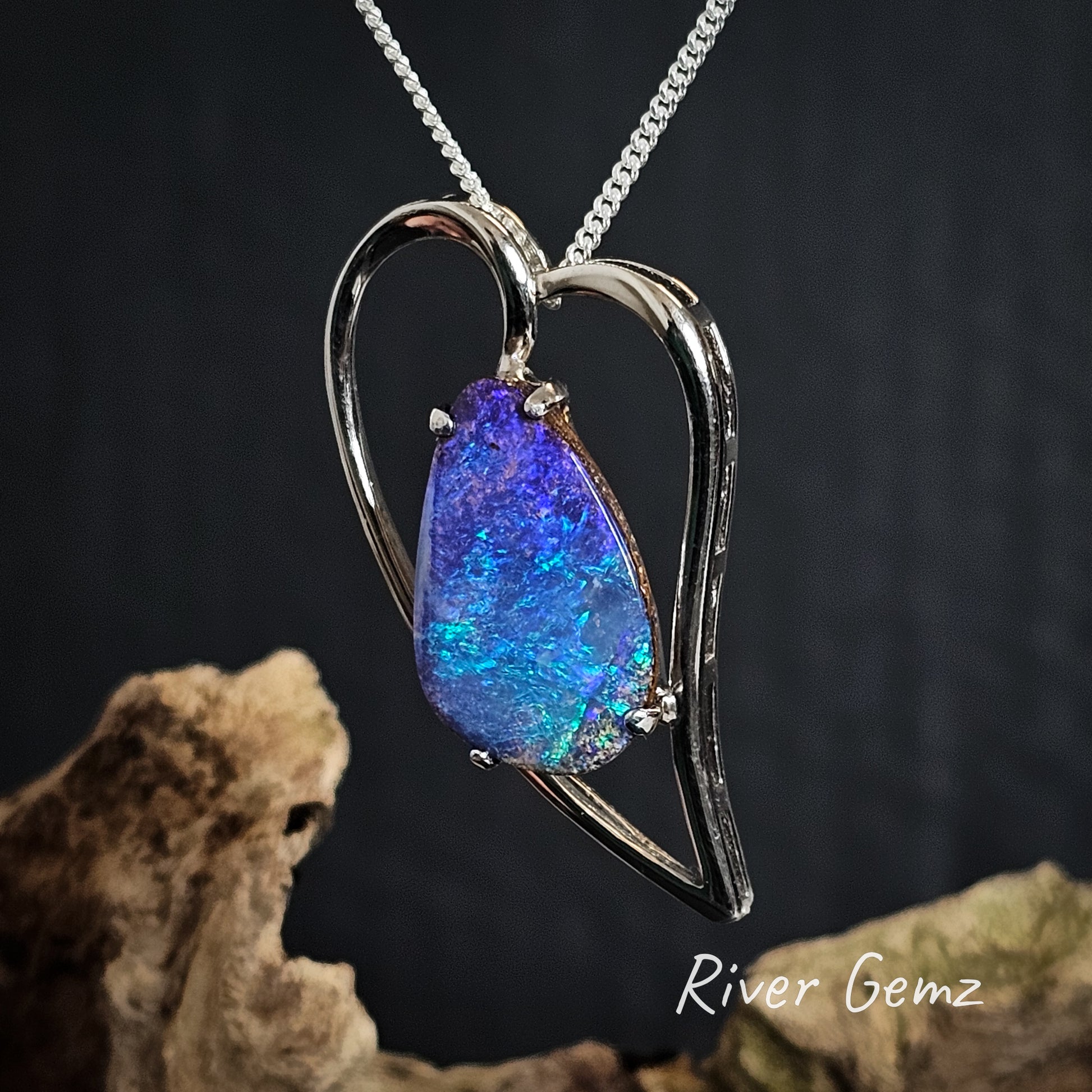Tear drop shaped boulder opal claw set in heart shaped silver necklace.