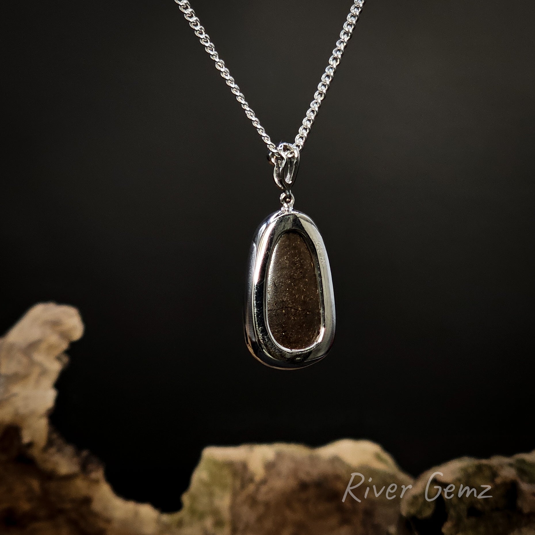 Rear view of the silver pendant shows the ironstone matrix of the boulder opal on a dark background