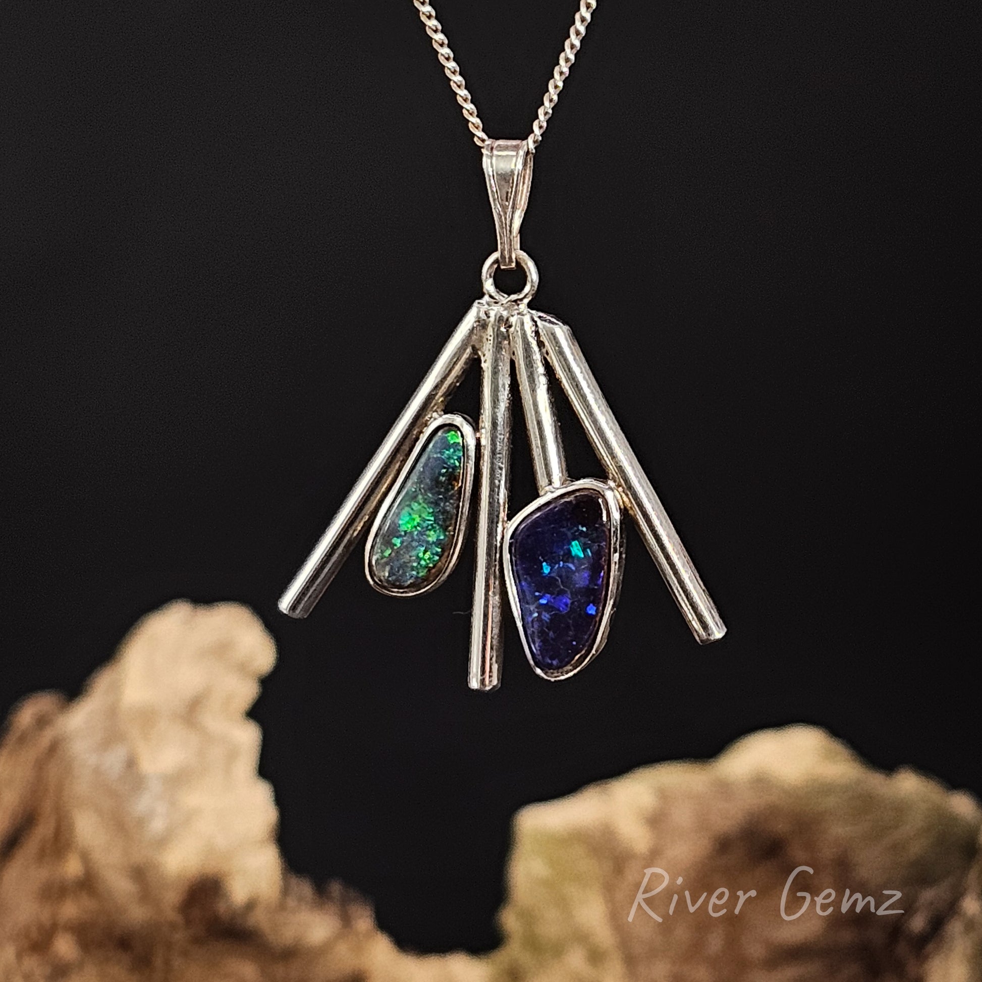 Silver pendant with two boulder opals on a dark background