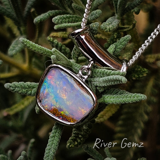 Multicoloured boulder opal in analog tv shaped besel silver setting. The silver chain passes through a horizontal pipe bail.