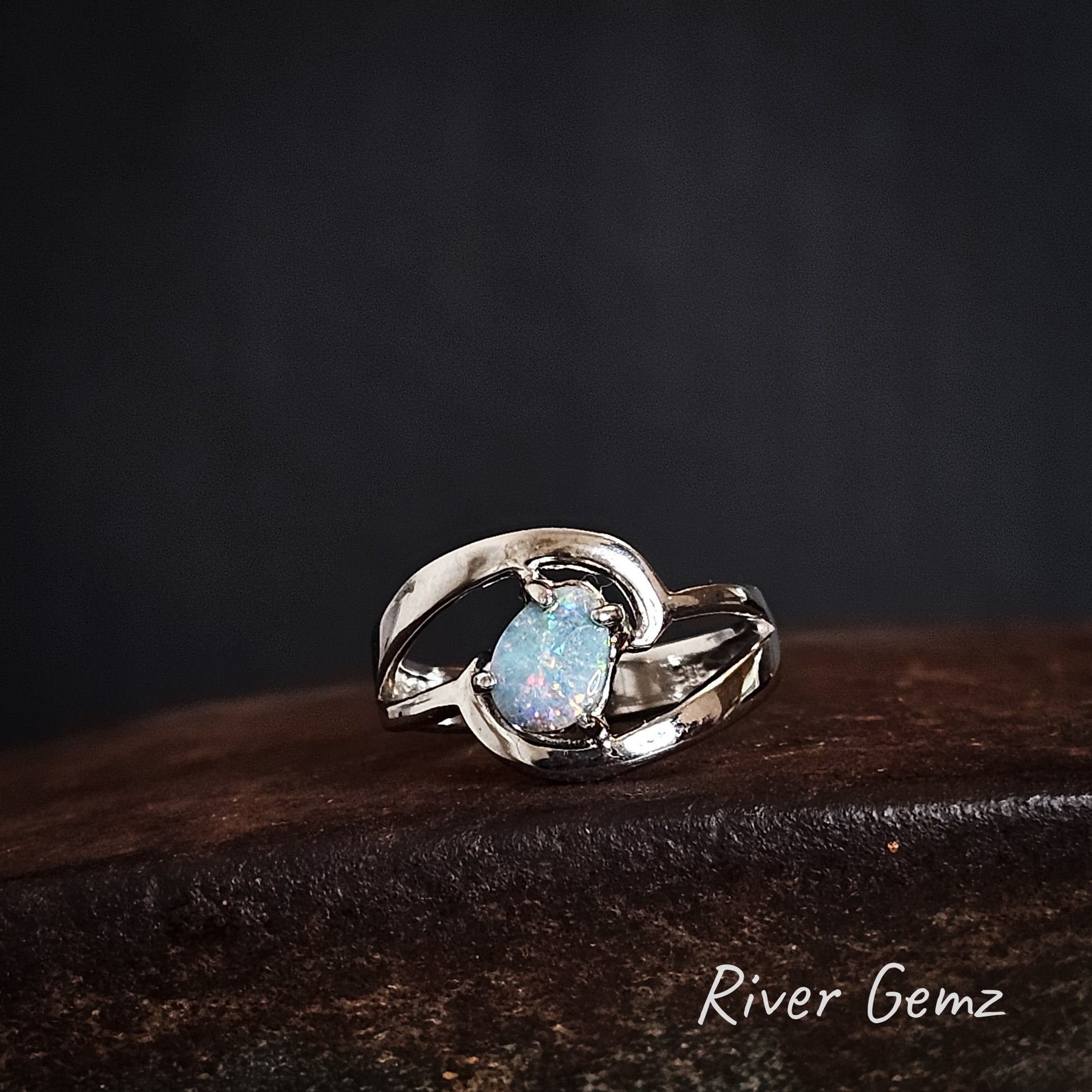 Silver ring with a teardrop shaped blue gemstone on a dark background, featuring the brand 'River Gemz'.