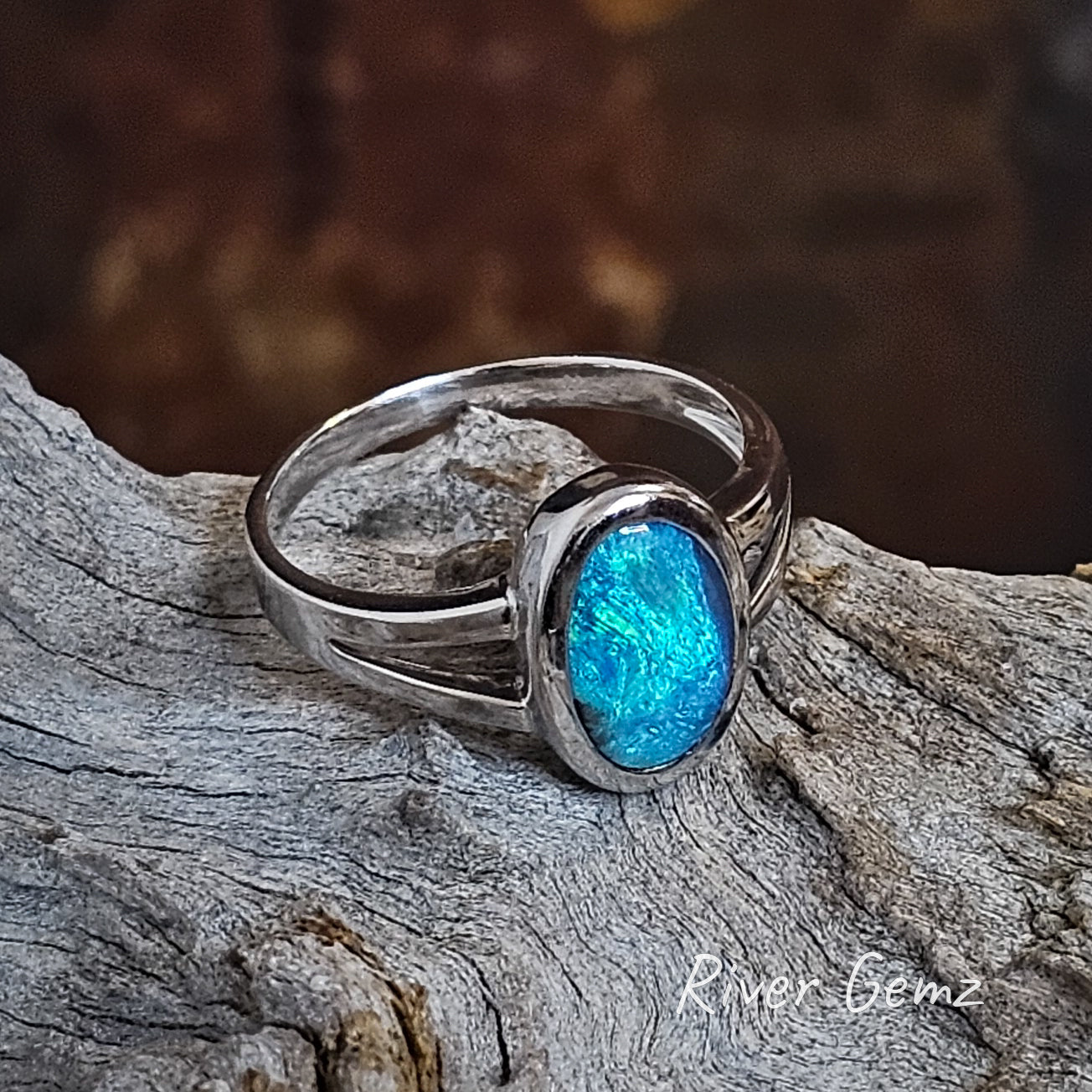 Oval shaped opal with blue and green swirls of colour besel set in silver ring.